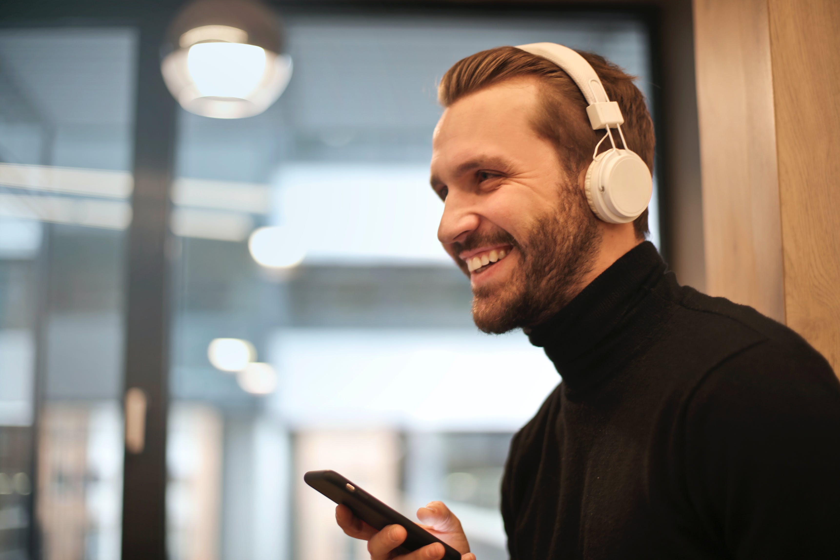 Un homme heureux qui parle à son téléphone à travers des écouteurs | Source : Pexels