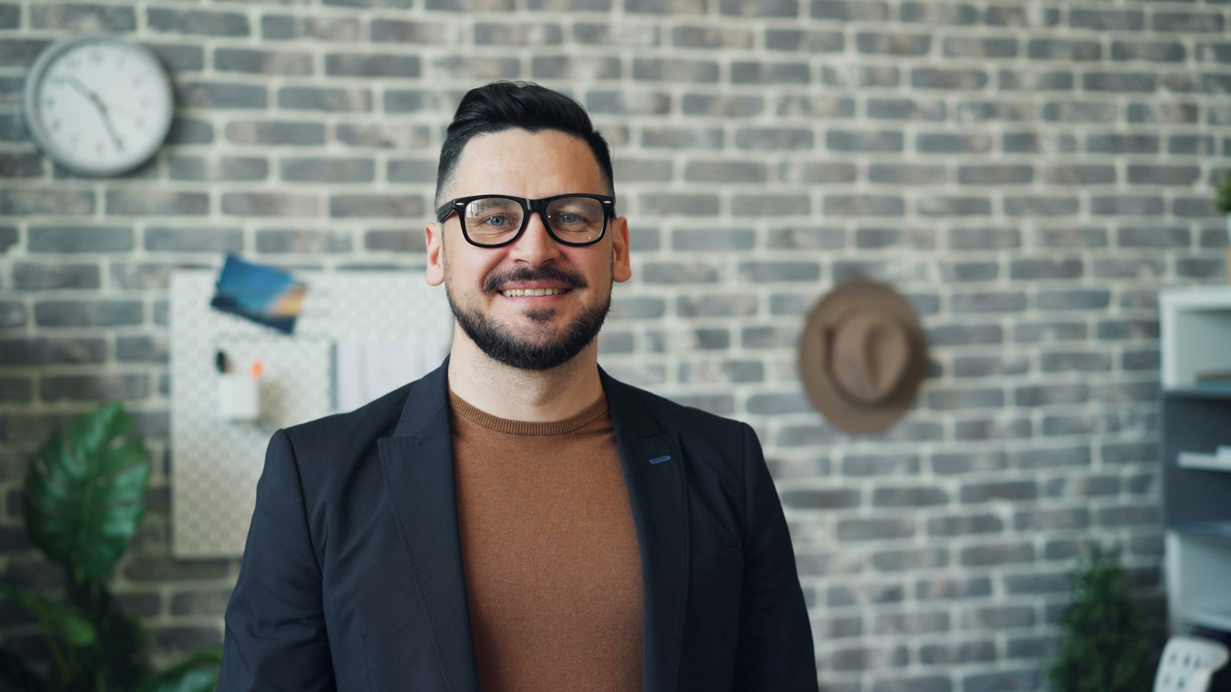 Un homme souriant debout devant un mur de briques | Source : Unsplash