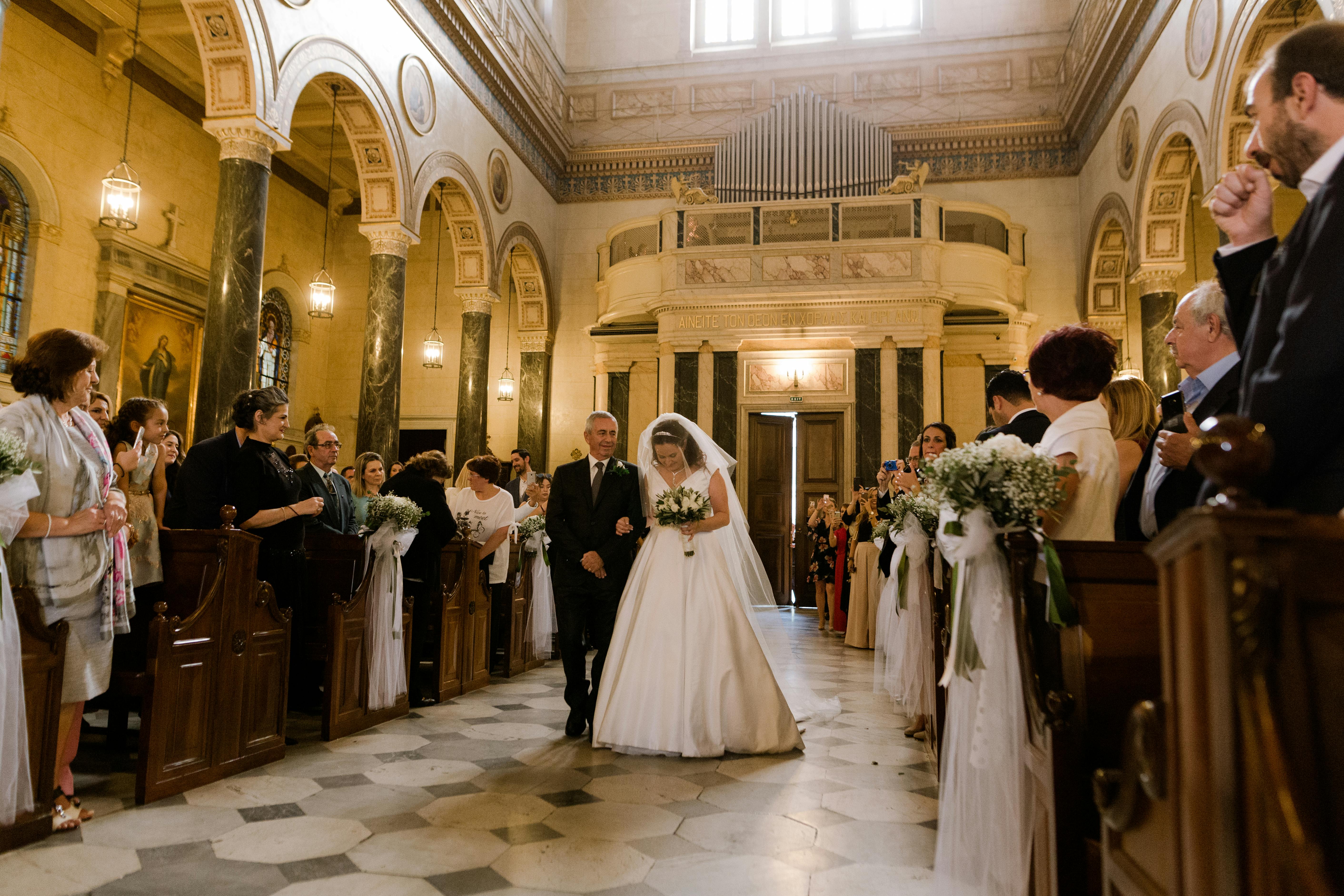 Un homme accompagne une mariée dans l'allée d'une église | Source : Pexels
