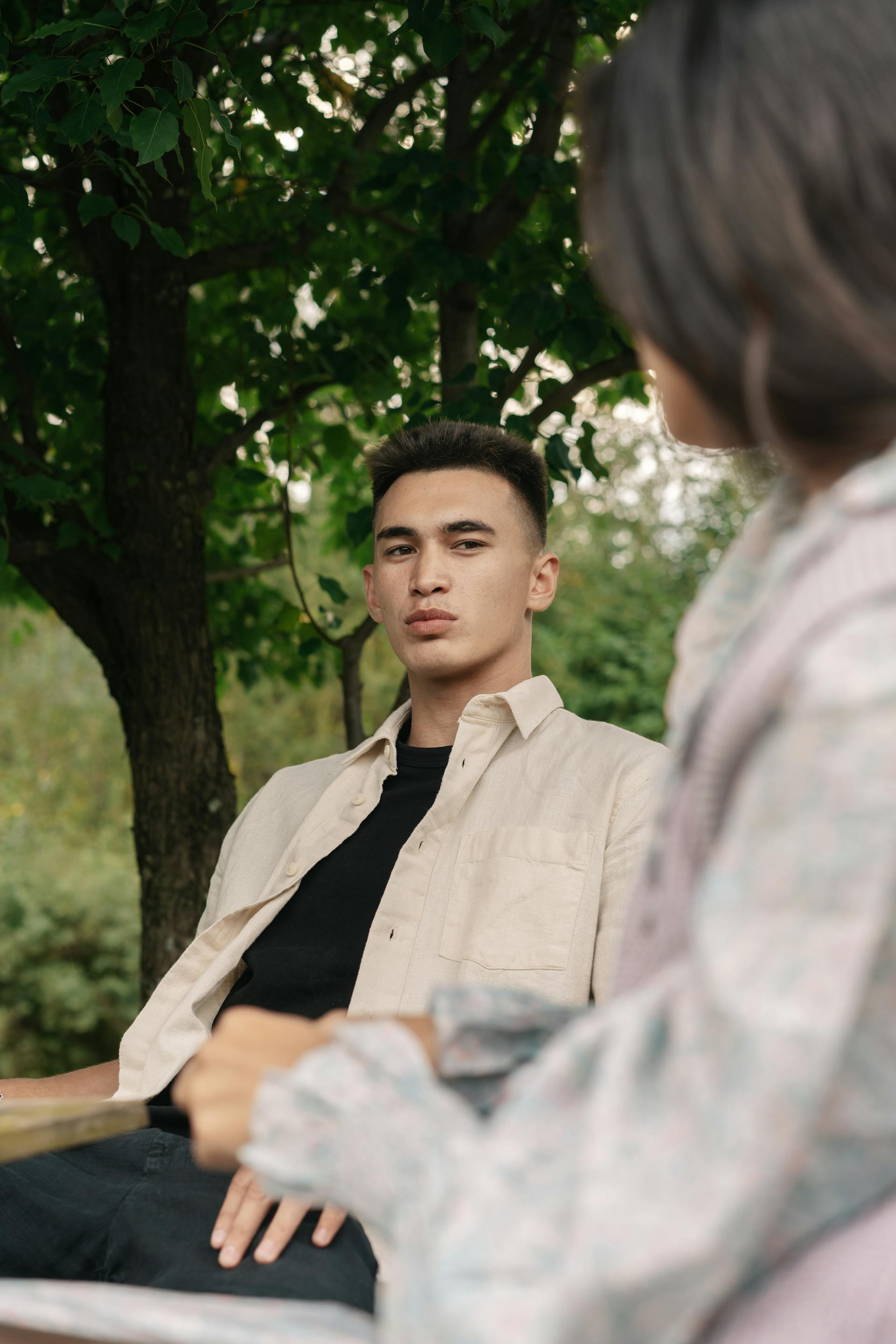 Un homme inquiet parle à une femme alors qu'il est assis à l'extérieur | Source : Pexels