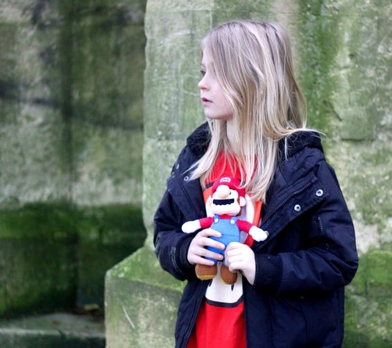 Une petite fille qui tien un nounours de Super Mario. | Photo : Unsplash