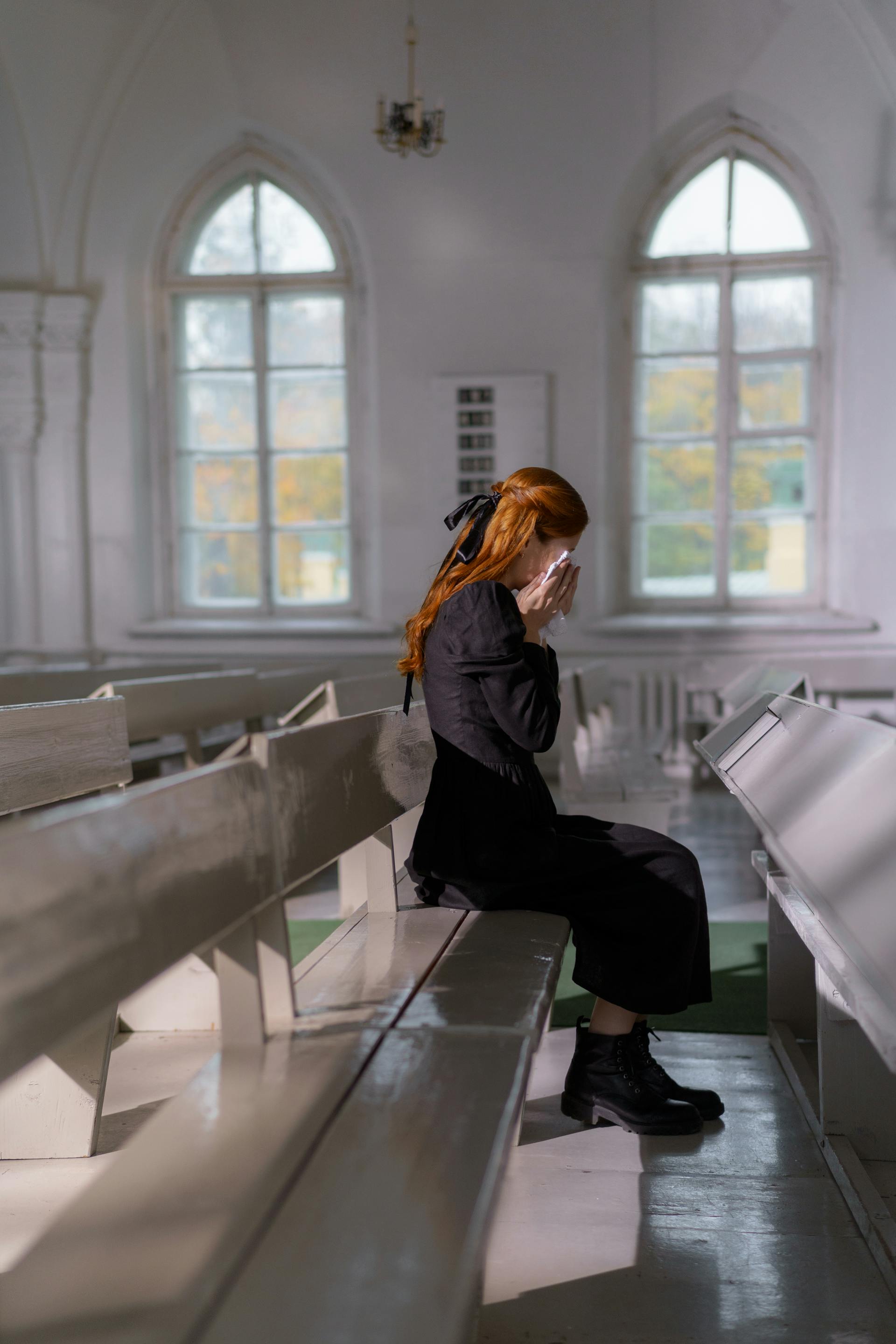 Une jeune femme assise à l'intérieur de l'église et en deuil | Source : Pexels