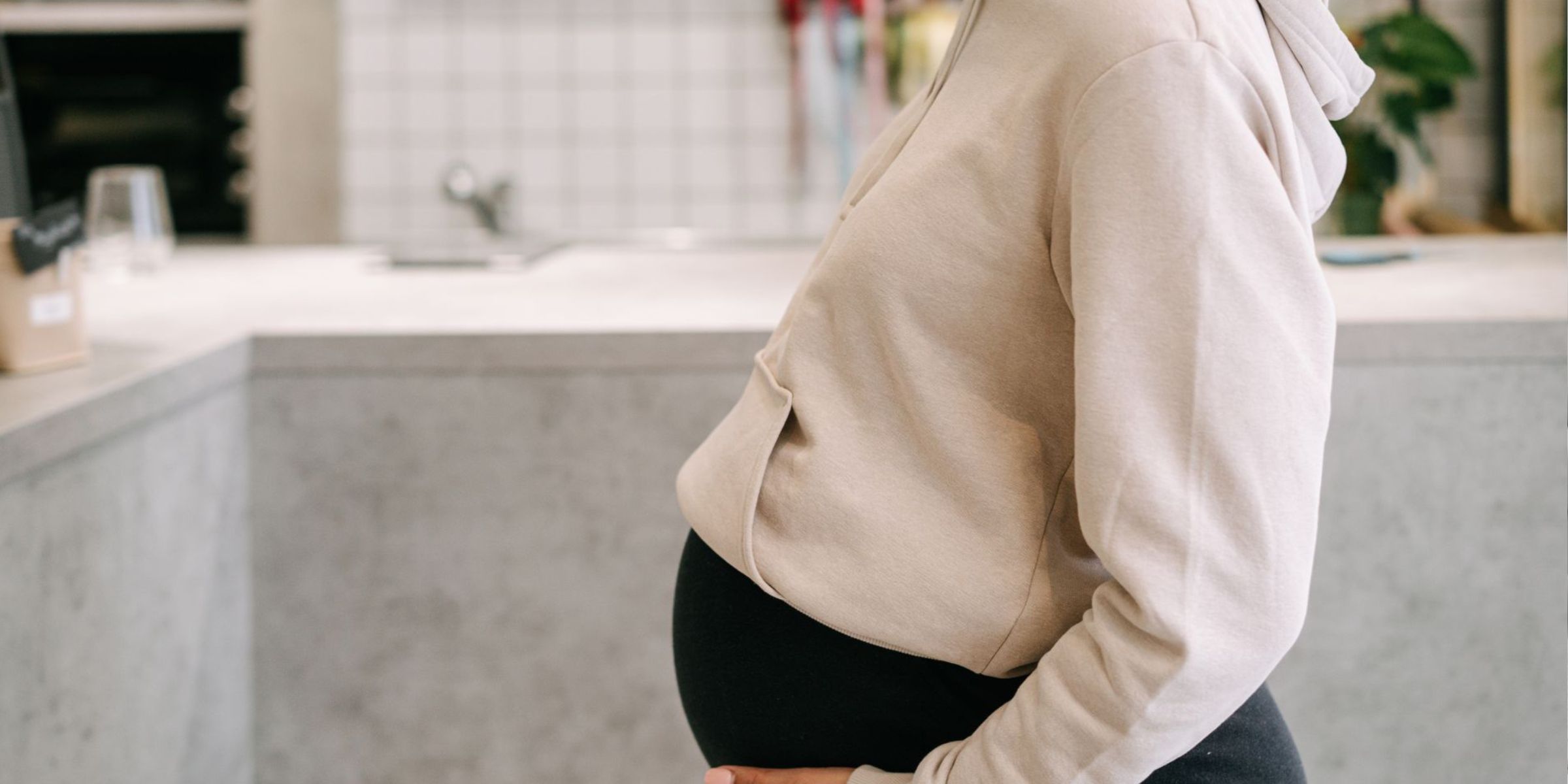 Une femme enceinte qui caresse doucement son ventre, debout dans une cuisine chaleureuse | Source : Pexels