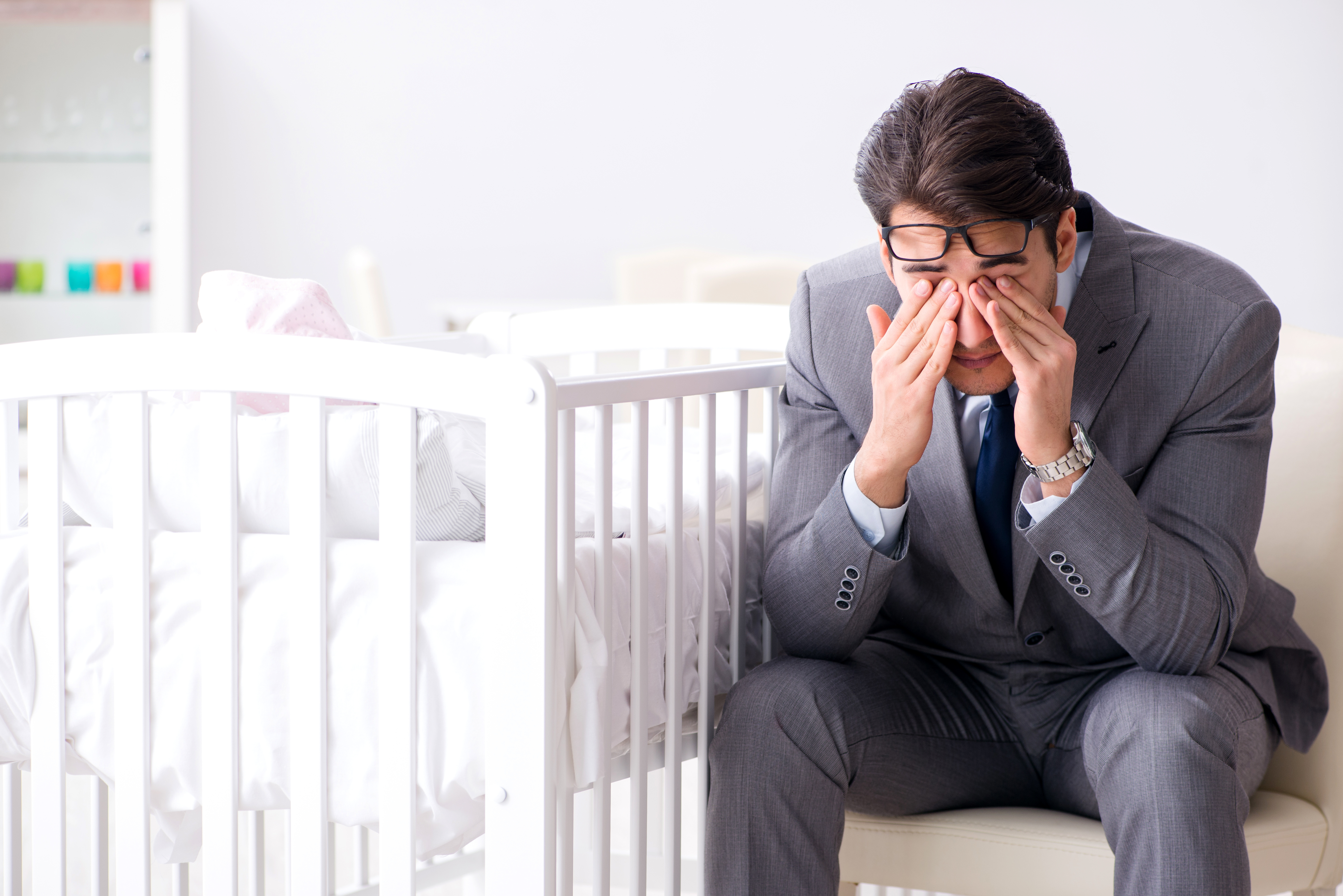 Un homme qui pleure assis à côté d'un lit de bébé vide | Source : Shutterstock