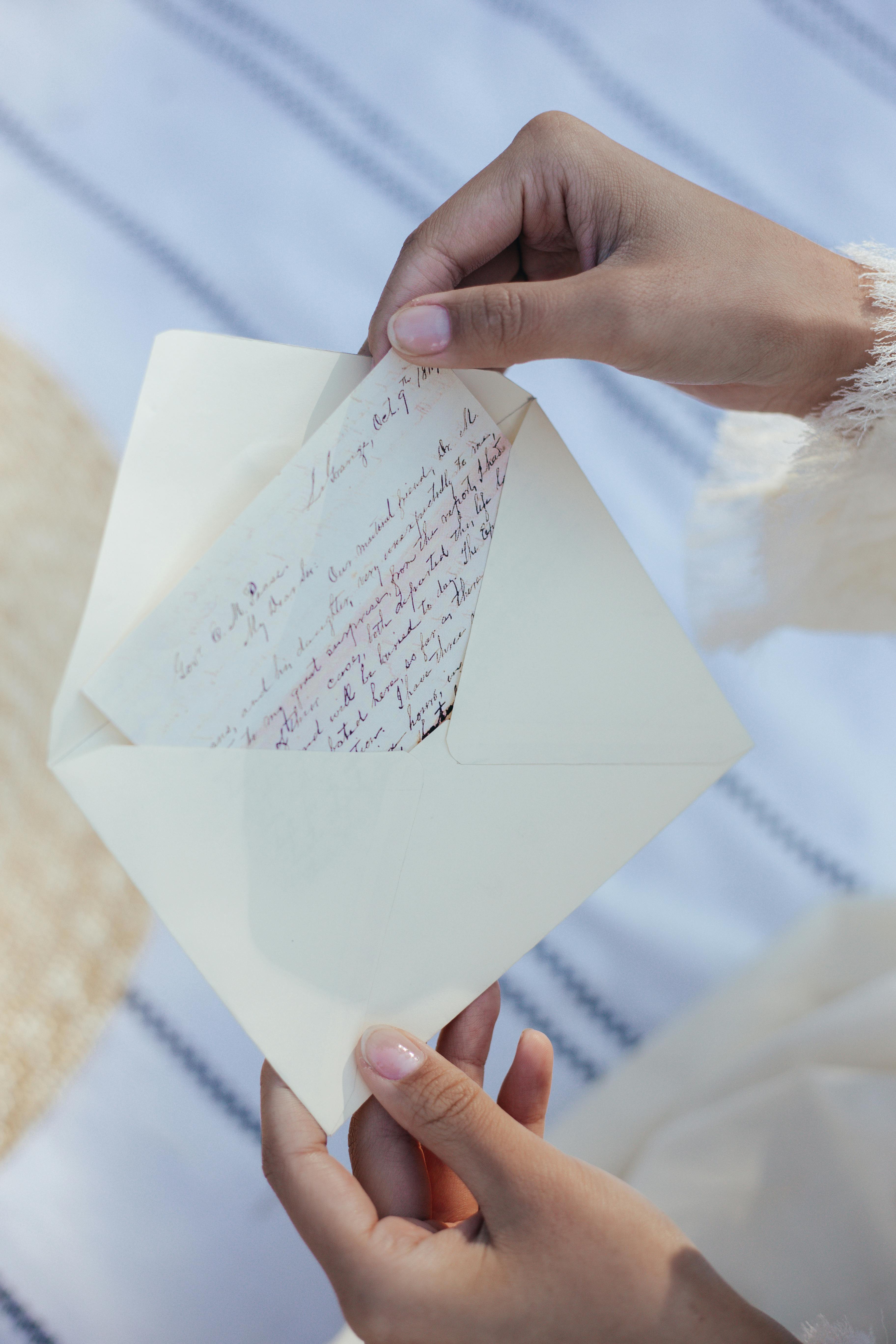 Une femme tient à la main une enveloppe avec une lettre manuscrite à l'intérieur | Source : Pexels