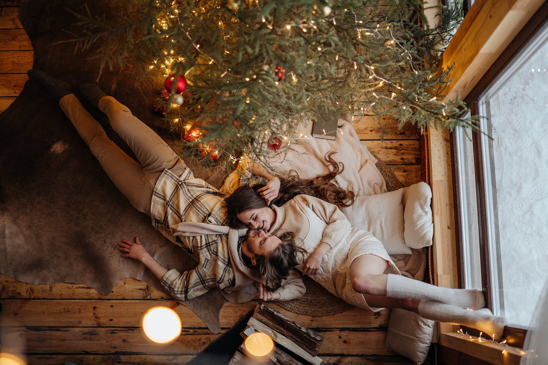 Un couple allongé à côté d'un sapin de Noël | Source : Pexels