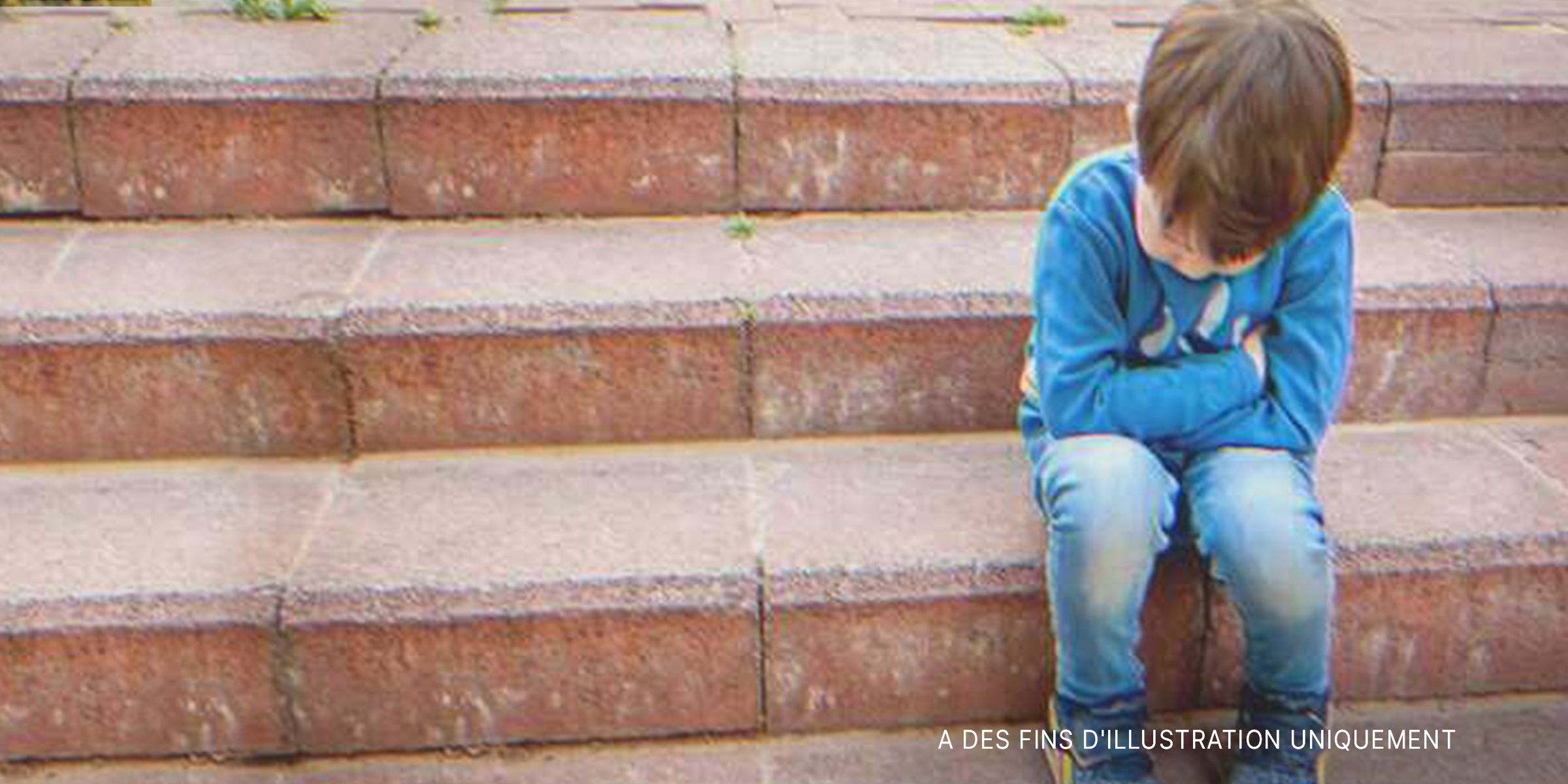 Un garçon bouleversé assis sur des marches | Source : Shutterstock