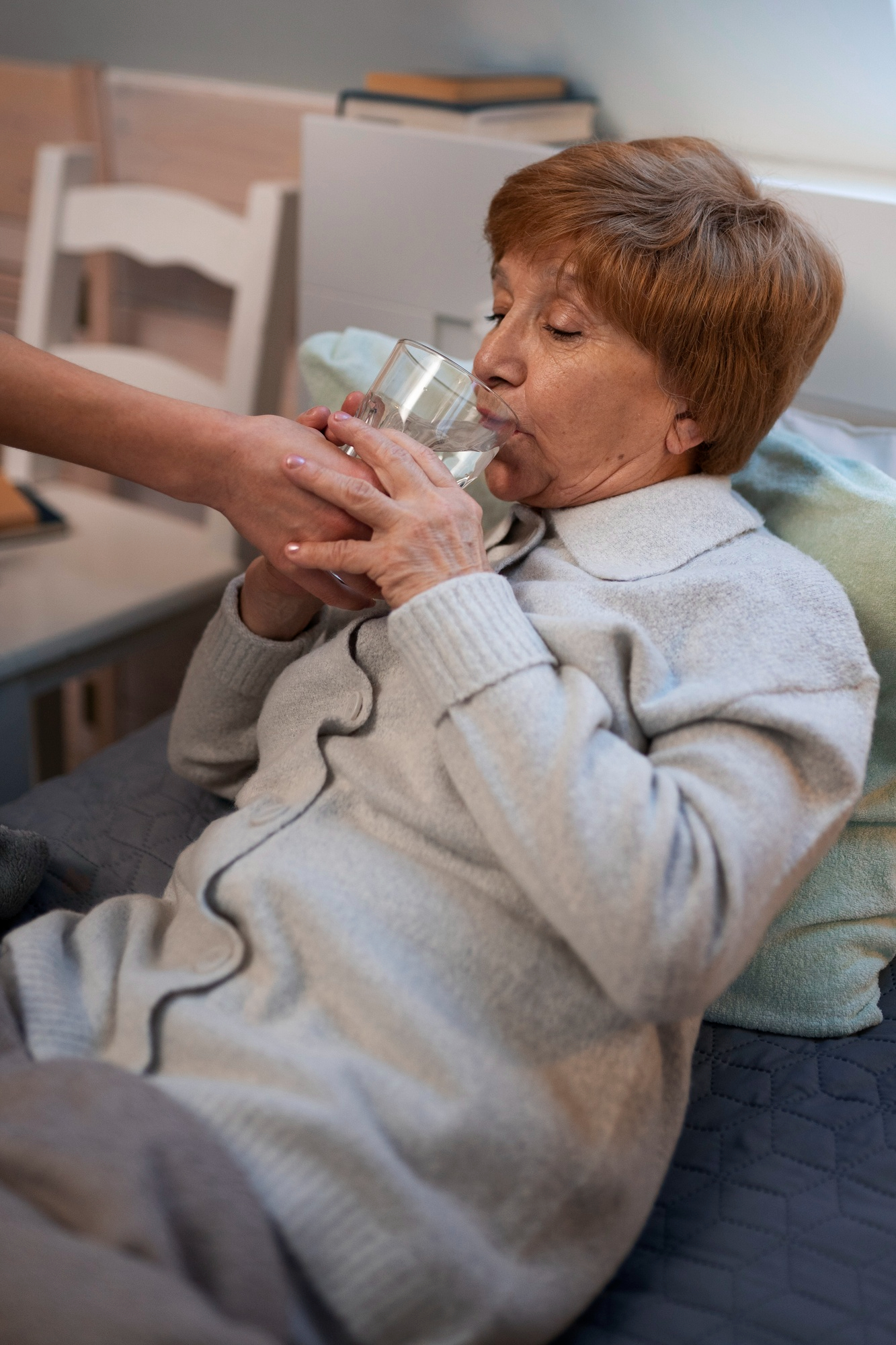 A woman helps a sick middle-aged woman drink water | Source: Freepik