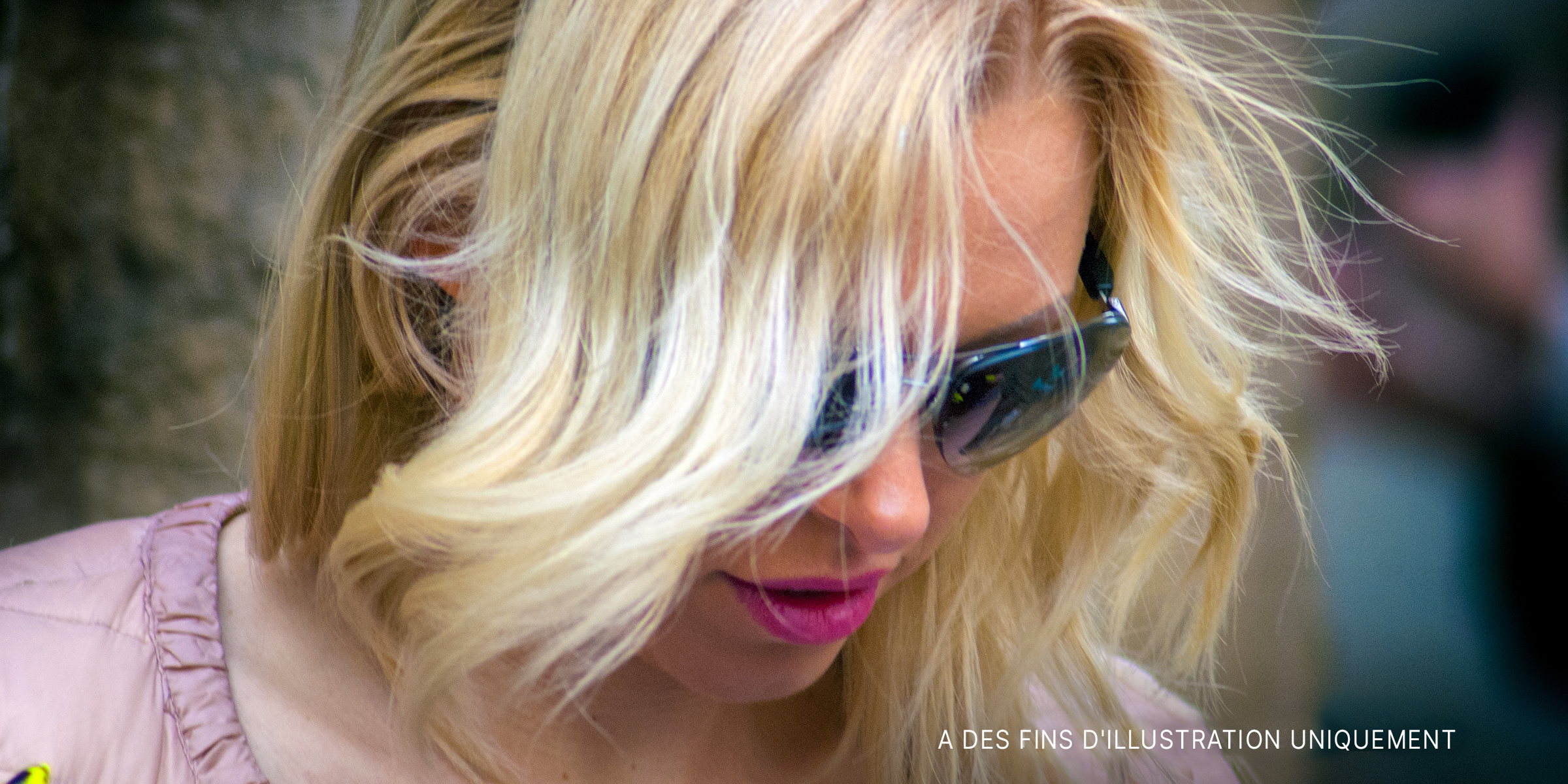 Une femme aux cheveux blonds qui regarde vers le bas en portant des lunettes de soleil | Source : Flickr.com/g_u/CC BY-SA 2.0