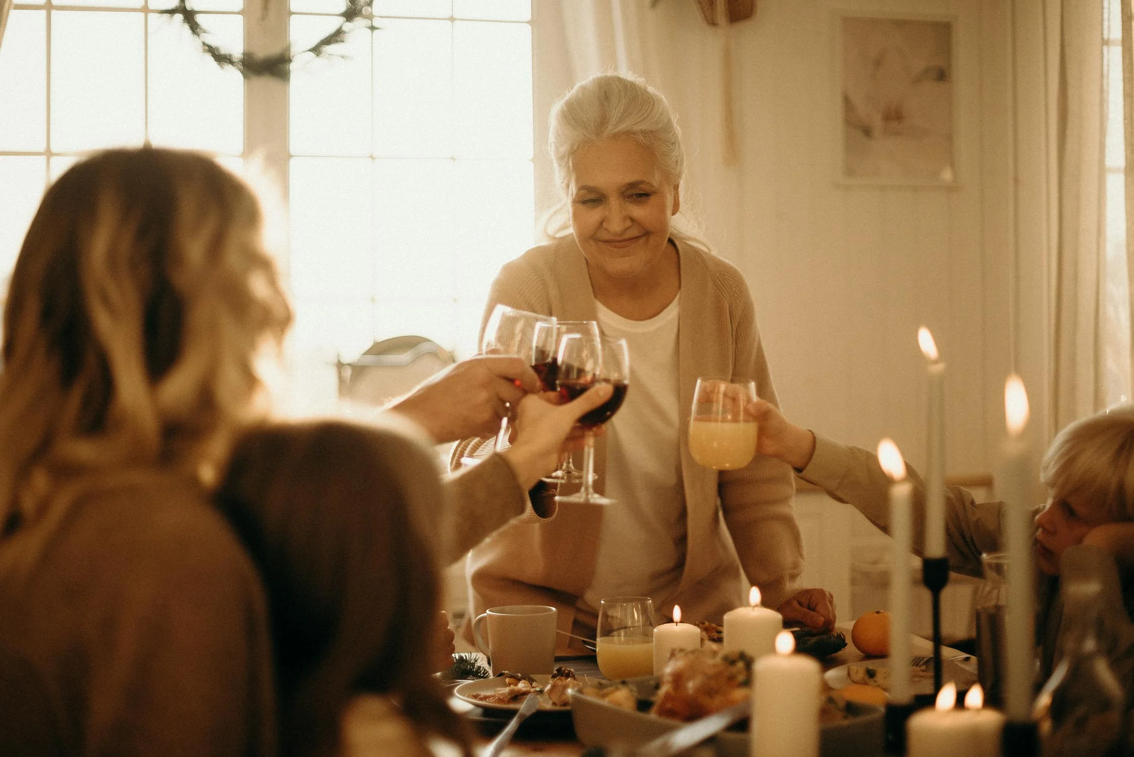 Une femme porte un toast lors d'un dîner Source : Pexels