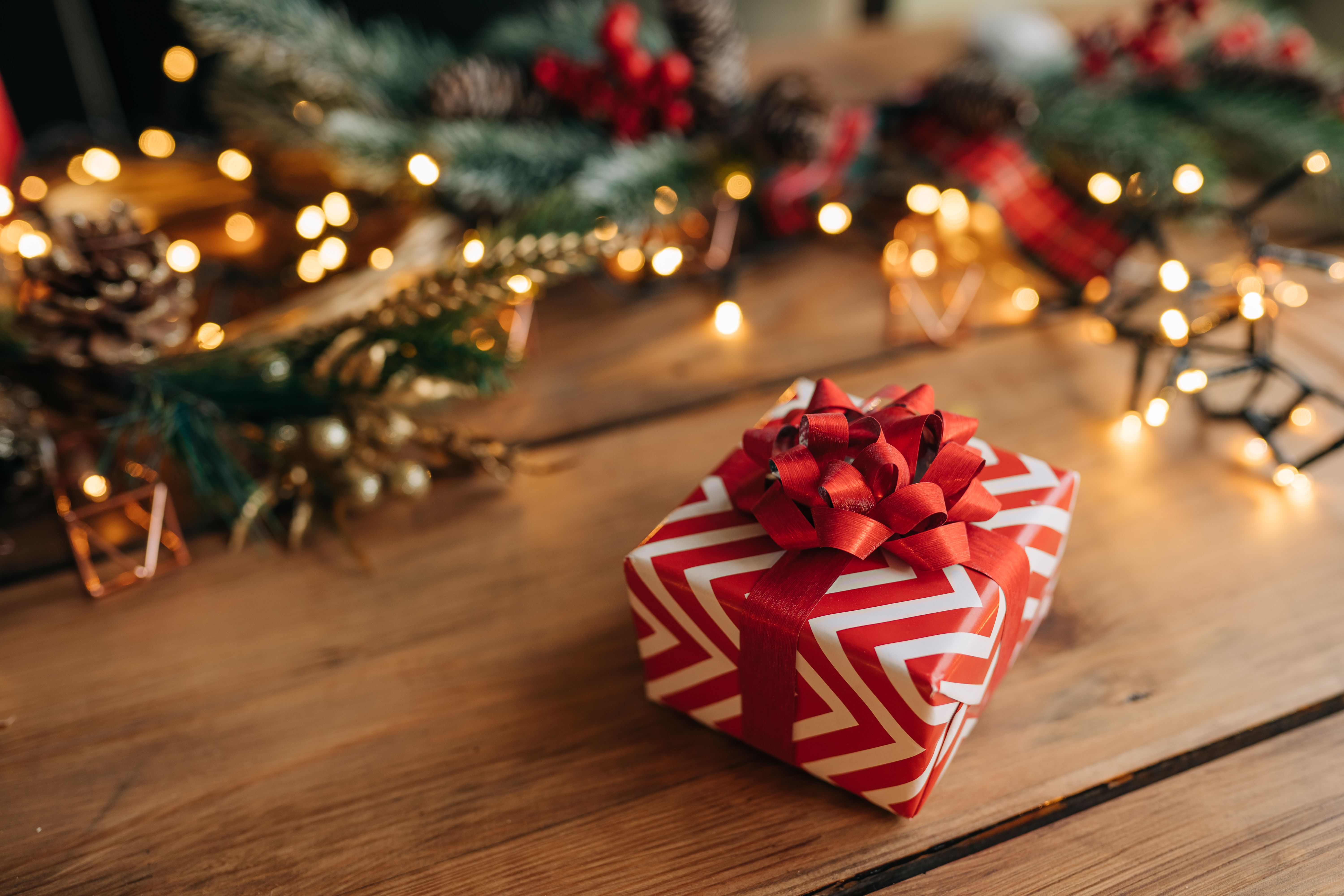 Un cadeau de Noël rouge et blanc posé sur une table en bois. | Source : Getty Images