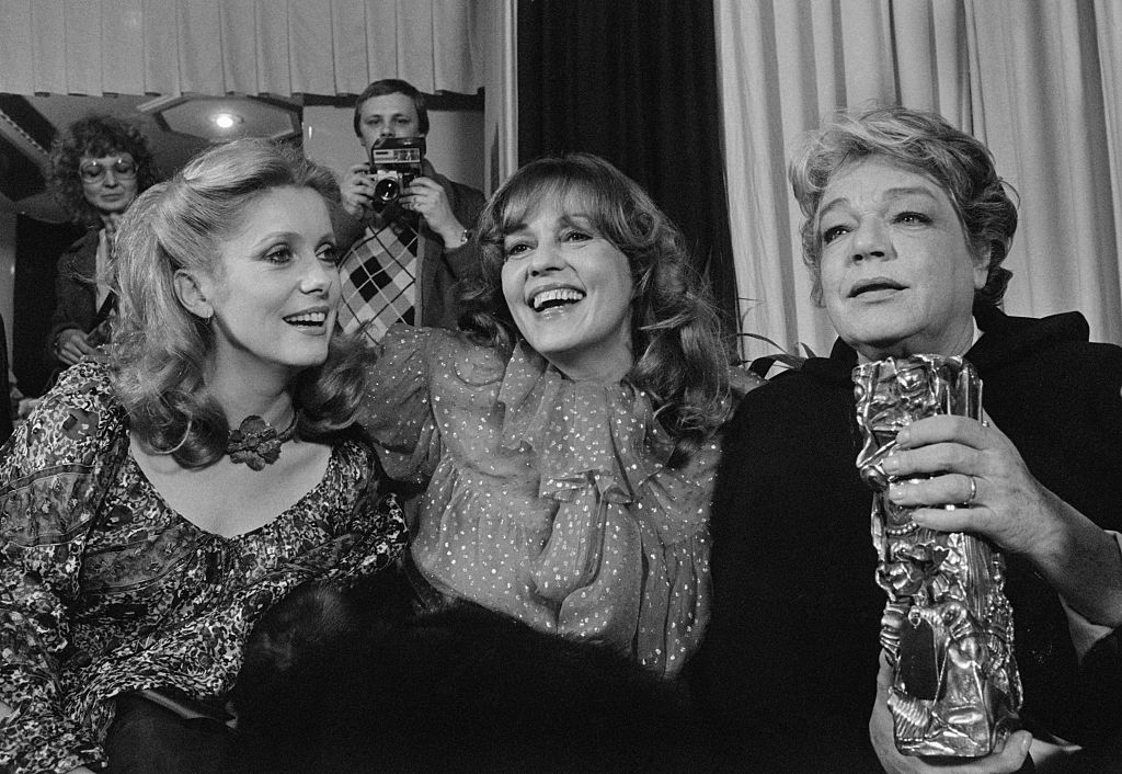 Les actrices françaises Catherine Deneuve, Jeanne Moreau et Simone Signoret rient ensemble lors de la cérémonie des César de 1978, qui s'est tenue au Théâtre de l'Empire à Paris. Signoret a remporté le César de la meilleure actrice pour son rôle dans La Vie devant soi. | Source : Getty Images