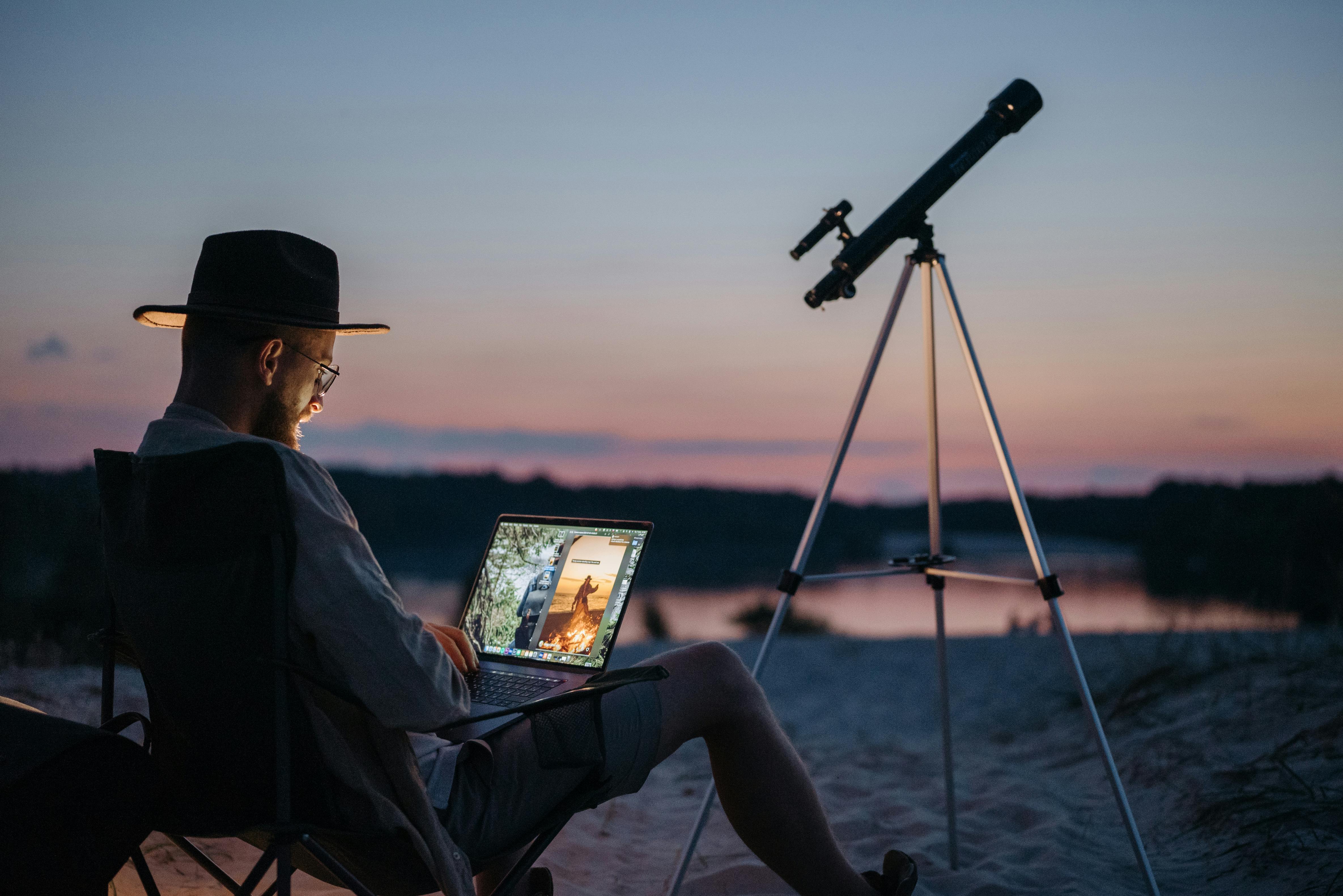 Un homme en plein air avec un télescope installé à proximité | Source : Pexels