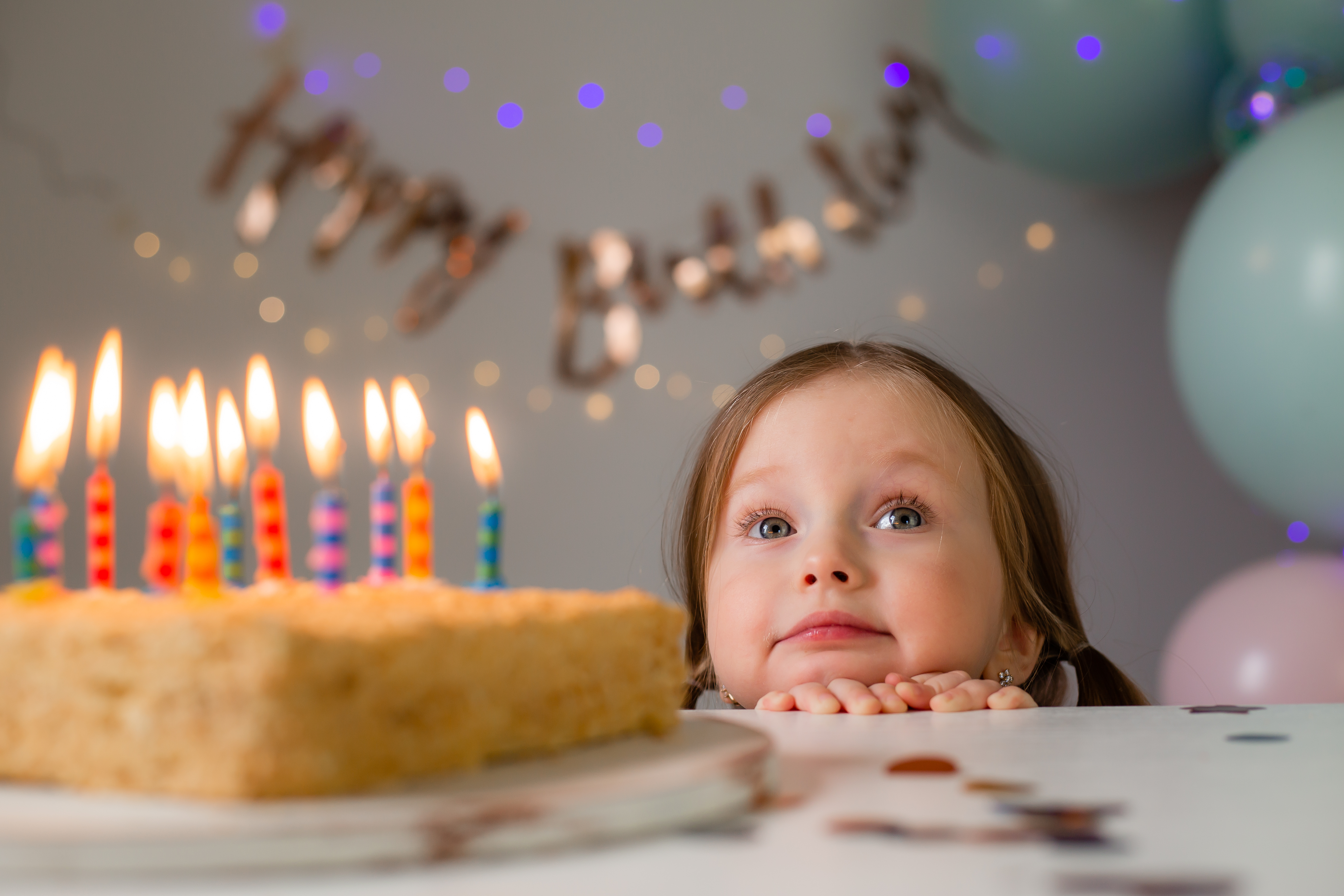 Une petite fille qui regarde par-dessus une table où se trouve un gâteau d'anniversaire | Source : Shutterstock