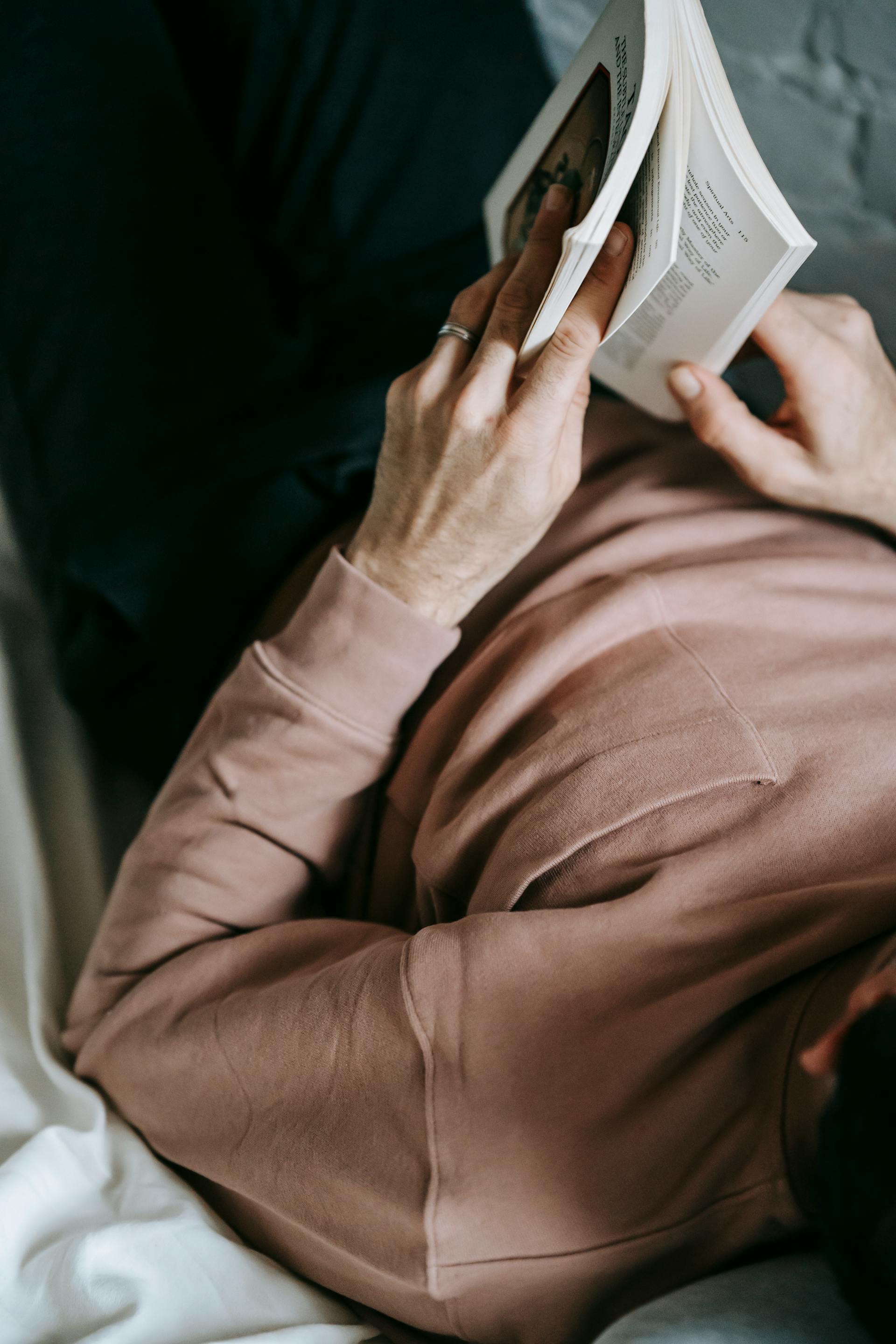 Gros plan sur un homme lisant un livre au lit | Source : Pexels