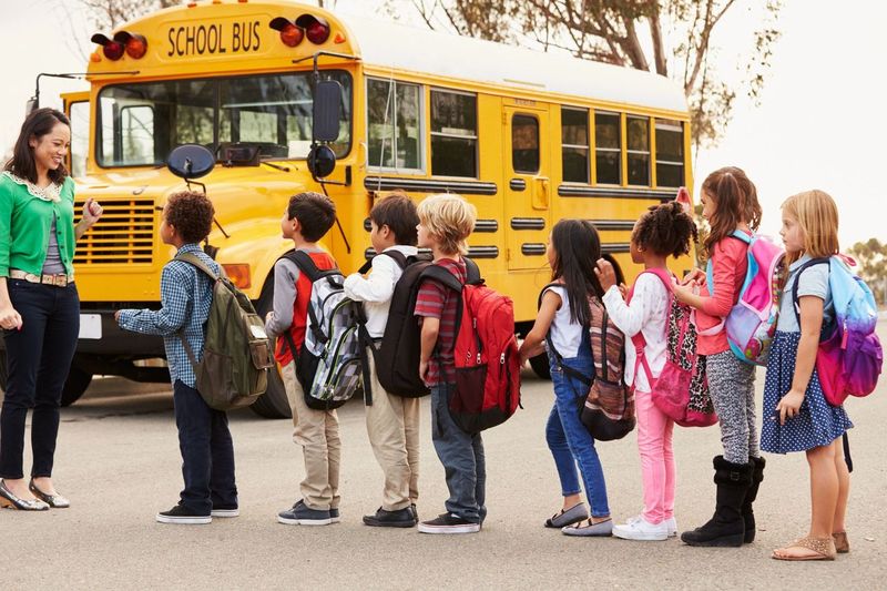 Élèves faisant la queue devant un bus scolaire | Source : Shutterstock
