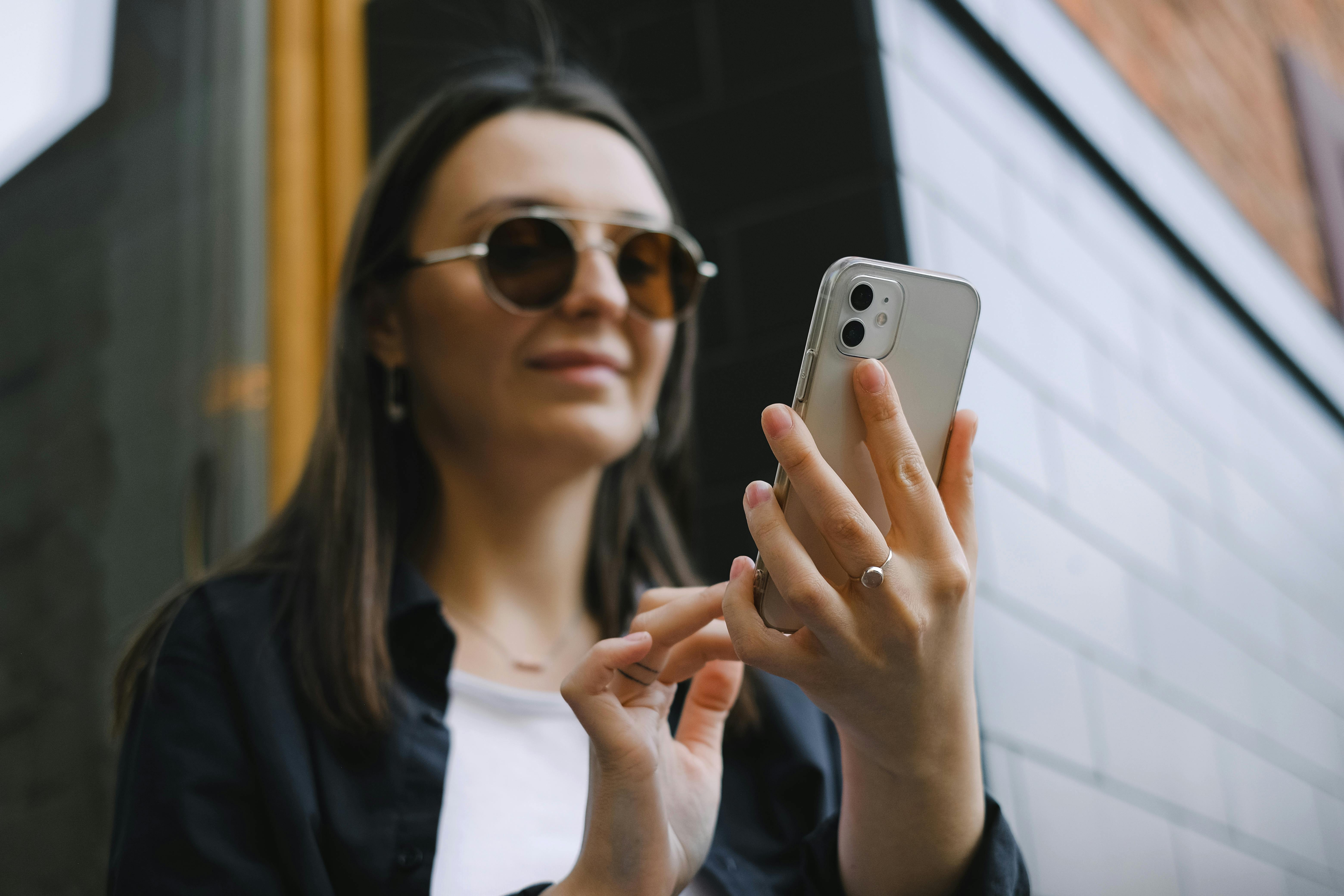 Une femme souriante qui tape sur son téléphone | Source : Pexels