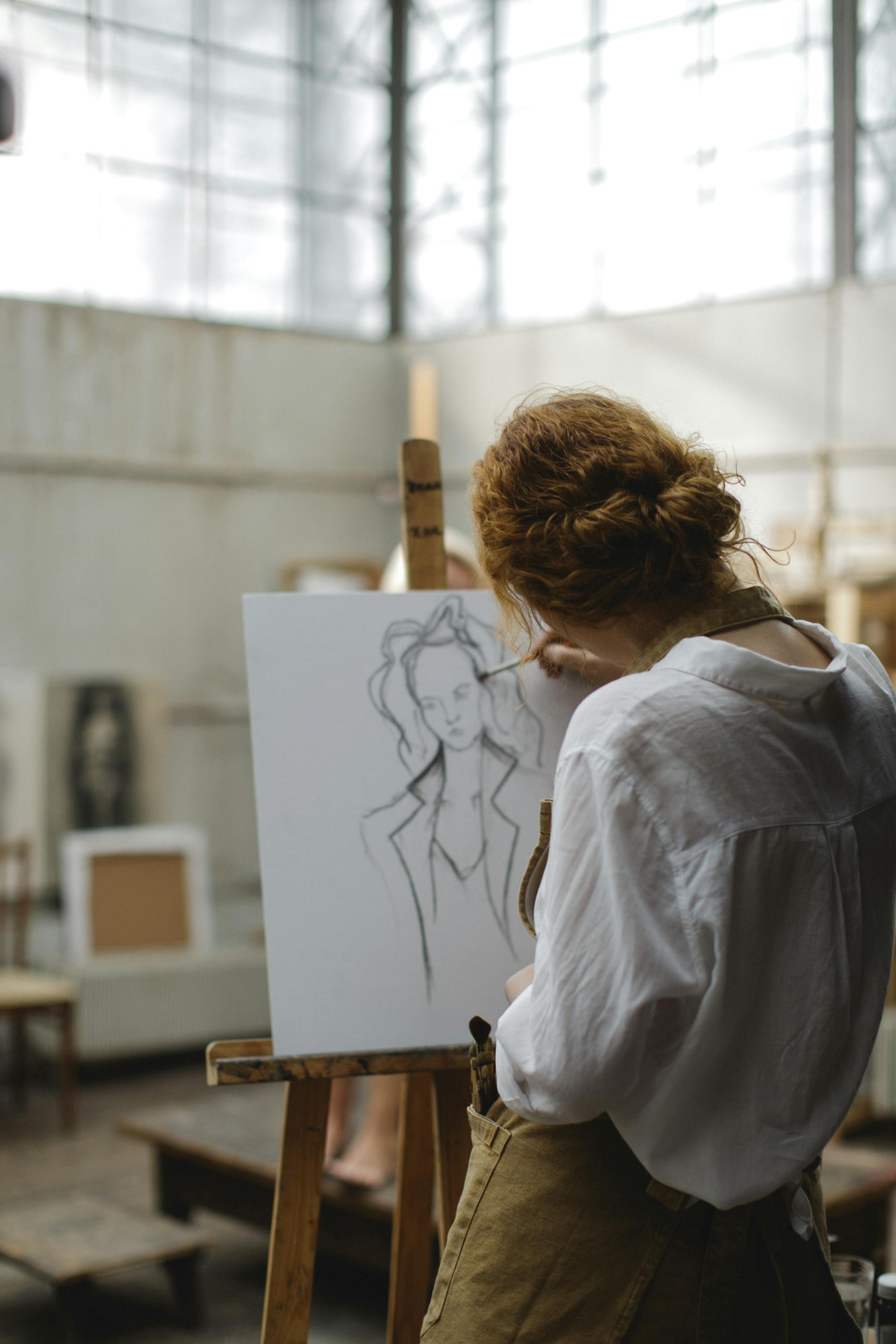 Vue arrière d'une femme en train d'esquisser une image sur un tableau blanc | Source : Pexels