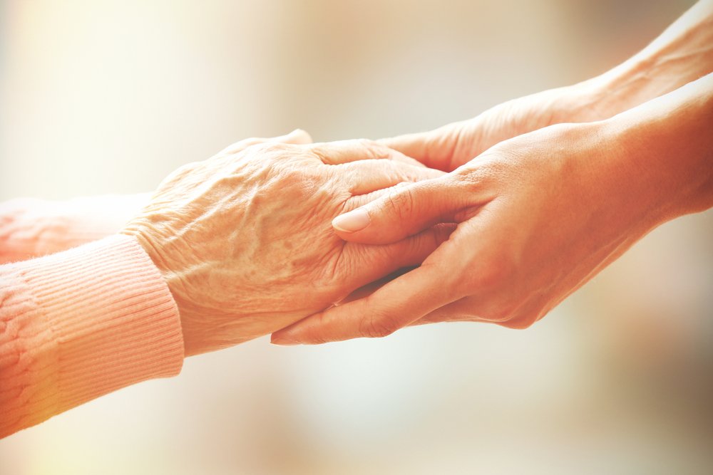 Les mains d'une personne âgée dépendante dans les mains d'une personne plus jeune. | Shutterstock