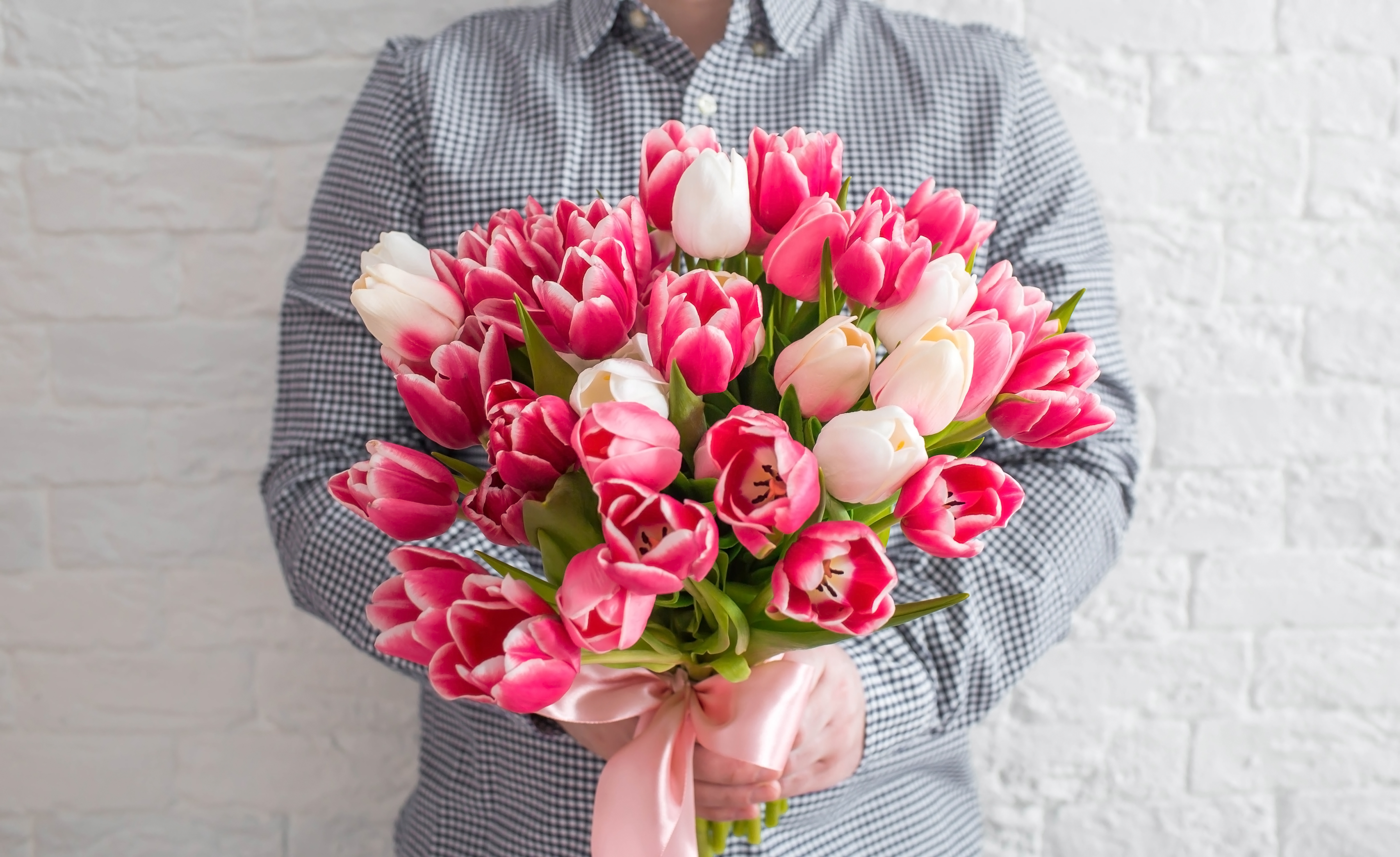 Un homme tenant un bouquet de tulipes blanches et roses | Source : Shutterstock