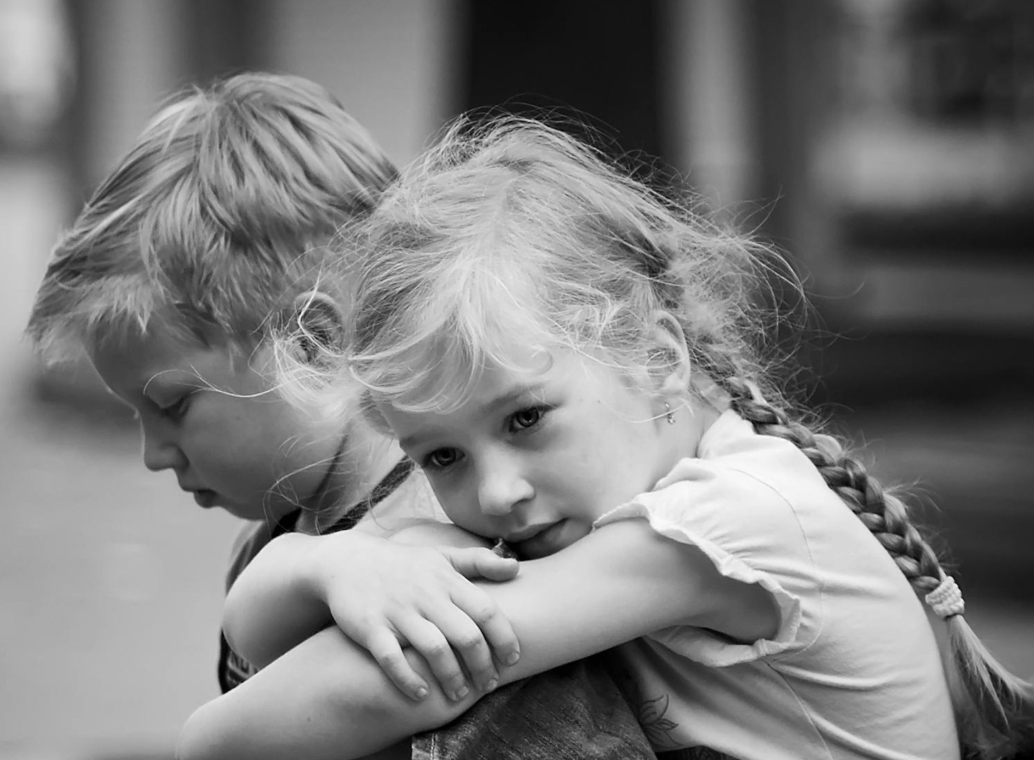 Photo en niveaux de gris d'un petit garçon et d'une petite fille tristes assis ensemble | Source : Pexels