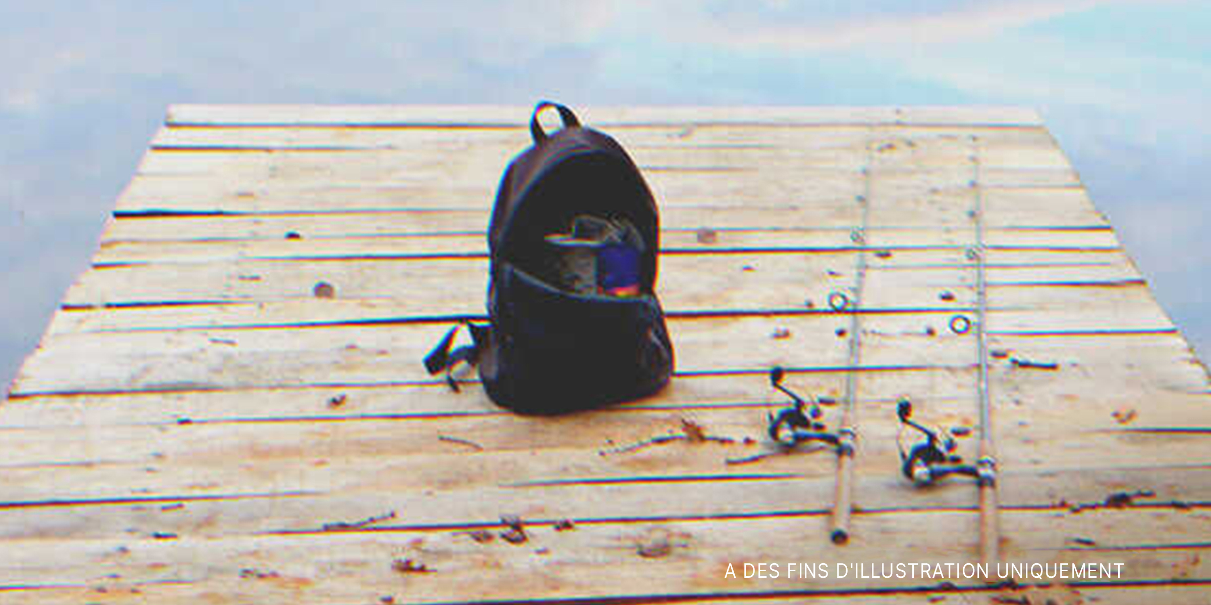 Des cannes à pêche et un sac à dos sur une planche de bois. | Source : Shutterstock