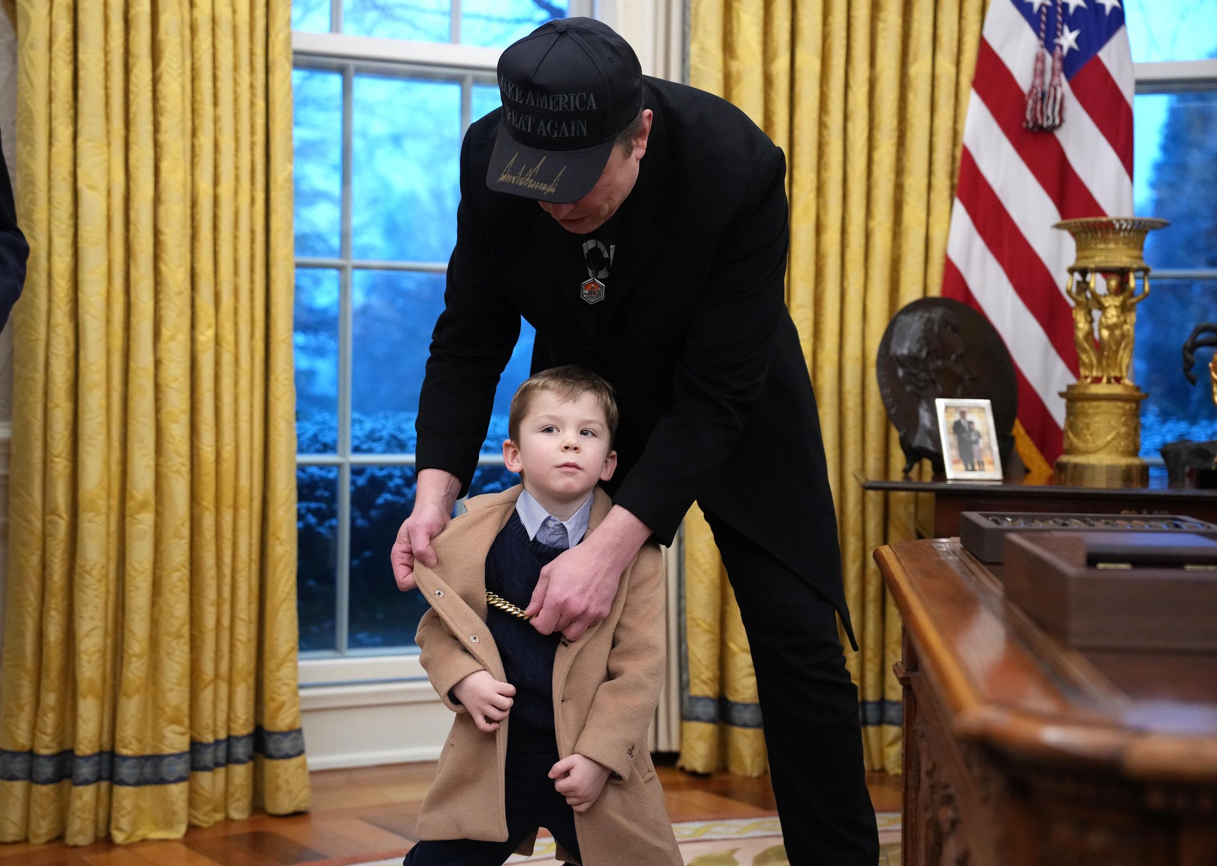 Elon Musk ajuste la veste de X Musk alors qu'ils rejoignent le président américain Donald Trump pour la signature d'un décret dans le bureau ovale de la Maison Blanche à Washington, DC, le 11 février 2025 | Source : Getty Images