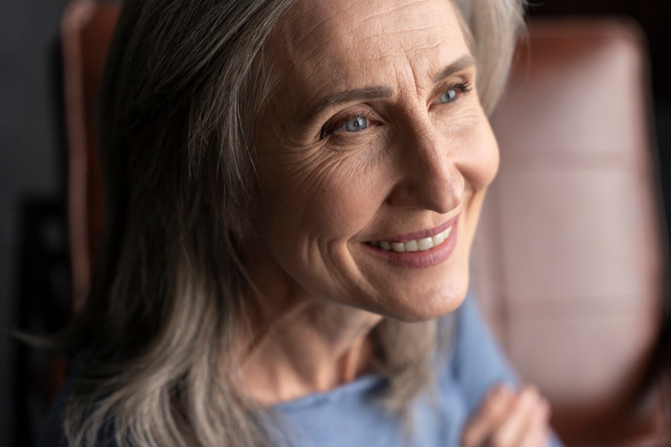 Une femme âgée souriante qui regarde de son côté | Source : Freepik