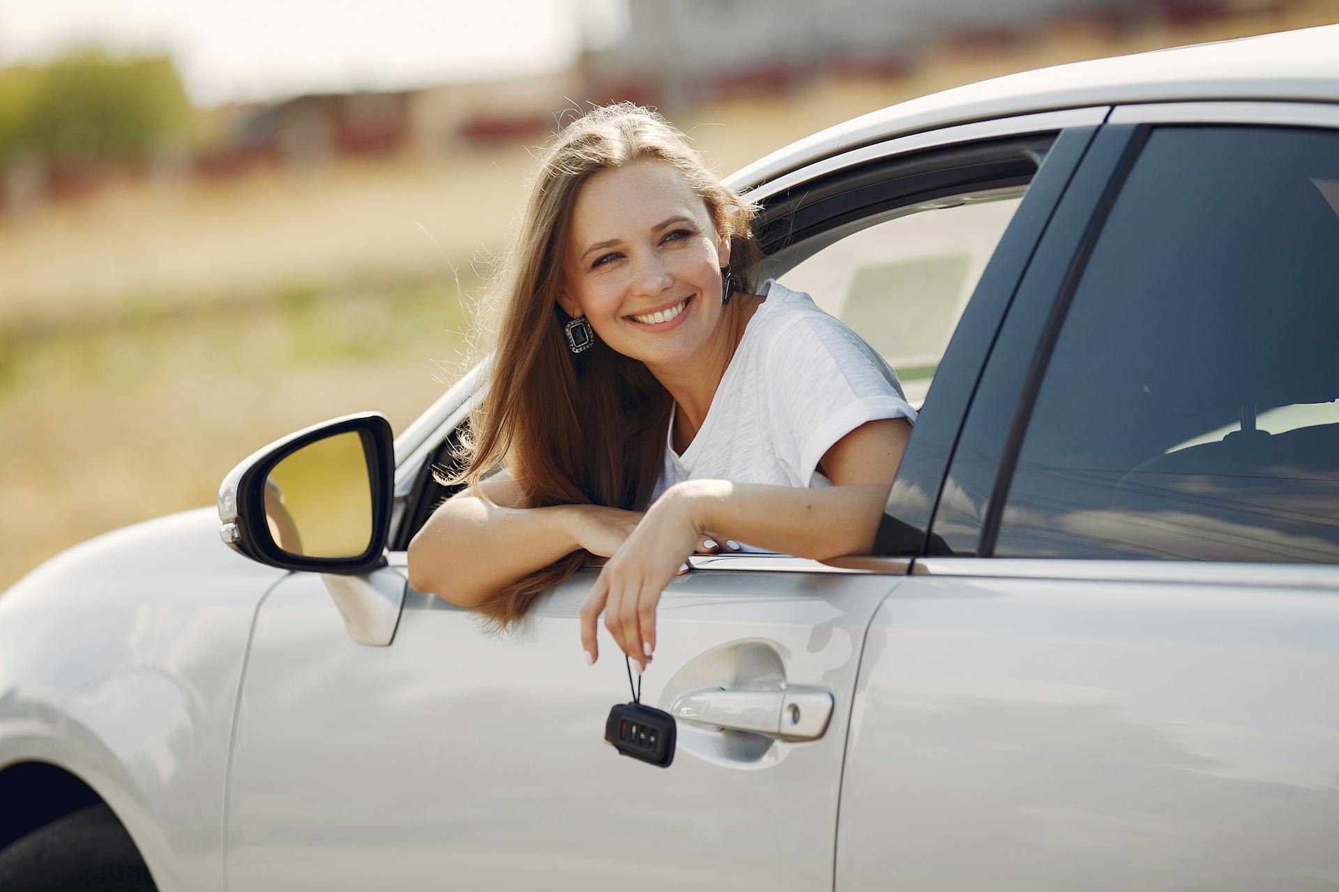 A woman peers out of a car window while holding keys | Source: Pexels