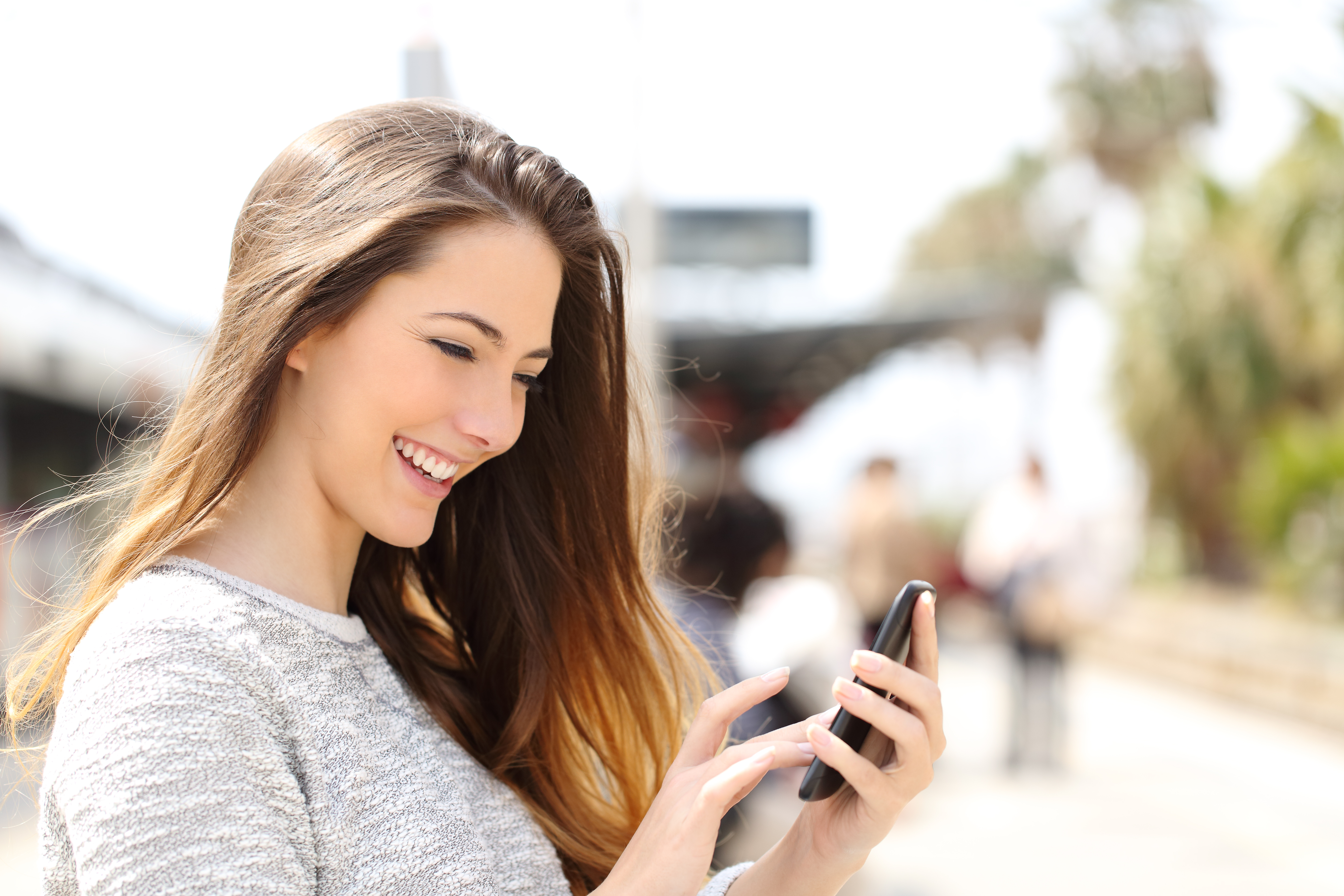Une jeune fille heureuse qui utilise son smartphone tout en marchant | Source : Shutterstock