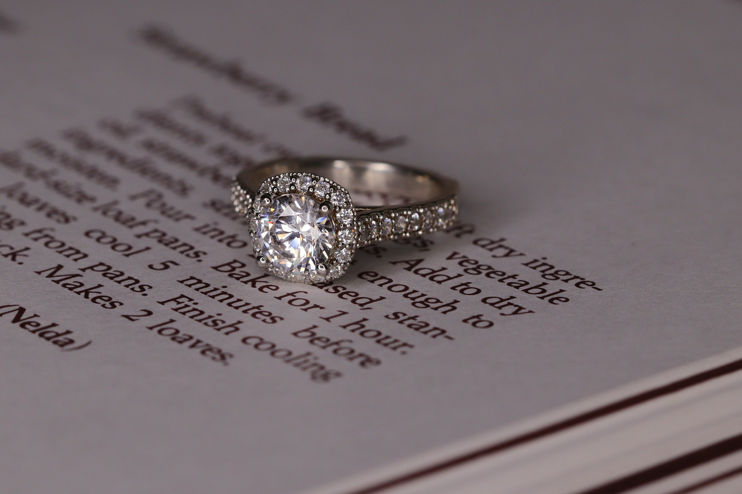 Une bague de fiançailles en or blanc avec un diamant sur un livre | Source : Unsplash