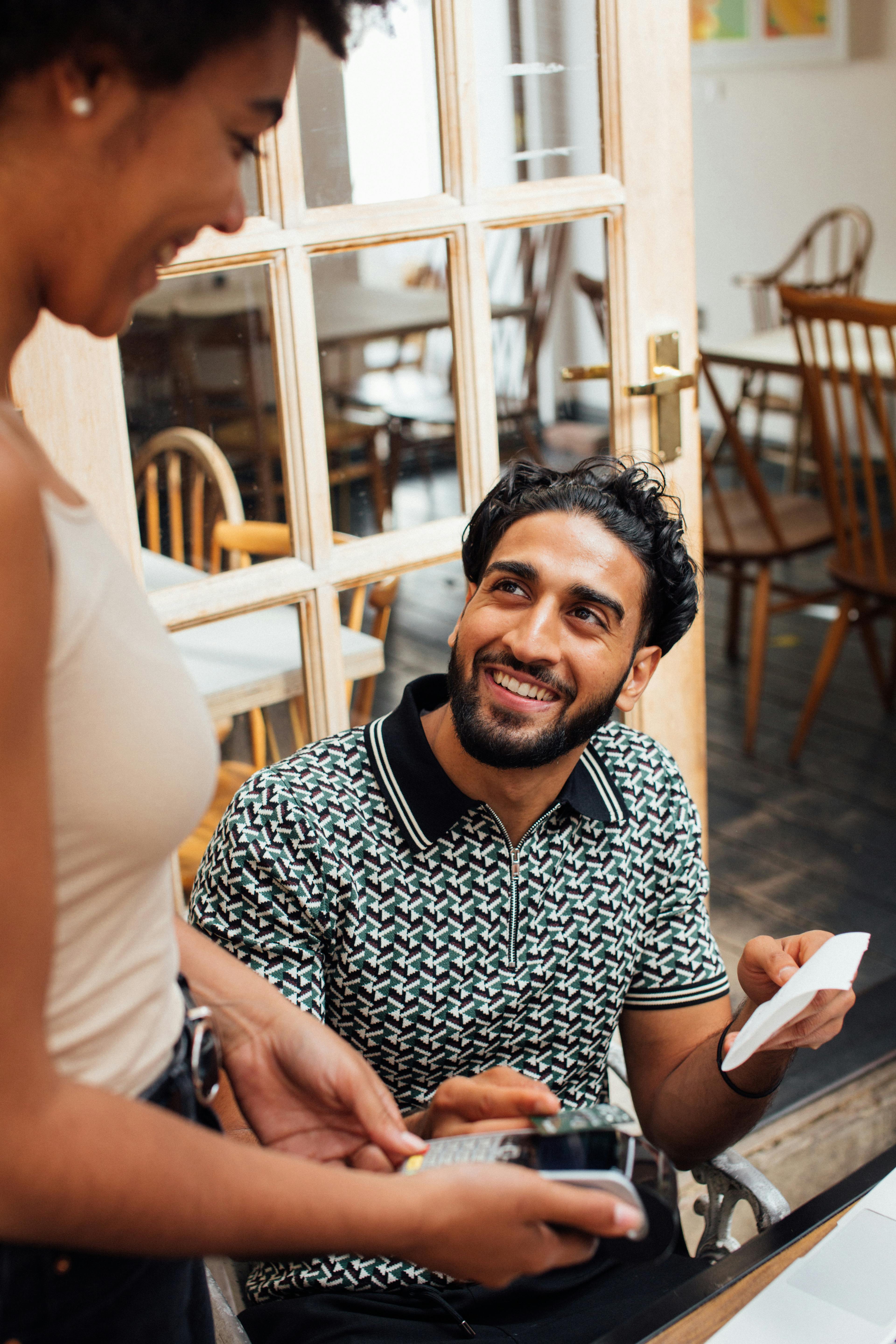 Homme souriant tout en parlant à une serveuse | Source : Pexels