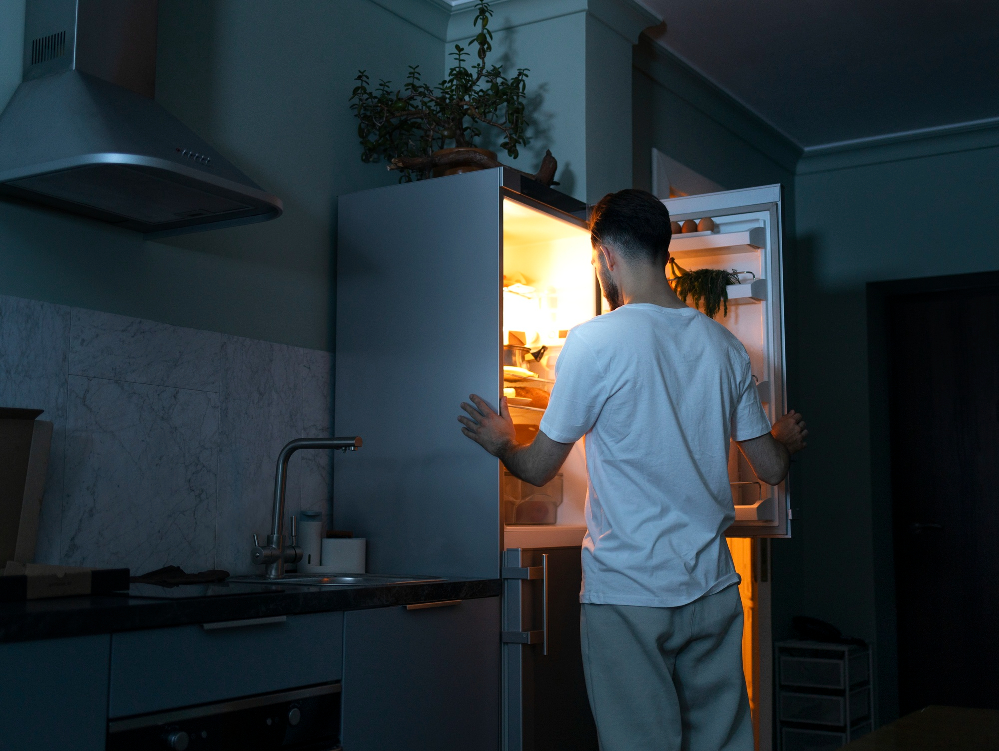 Un homme à la recherche d'en-cas dans le réfrigérateur | Source : Freepik