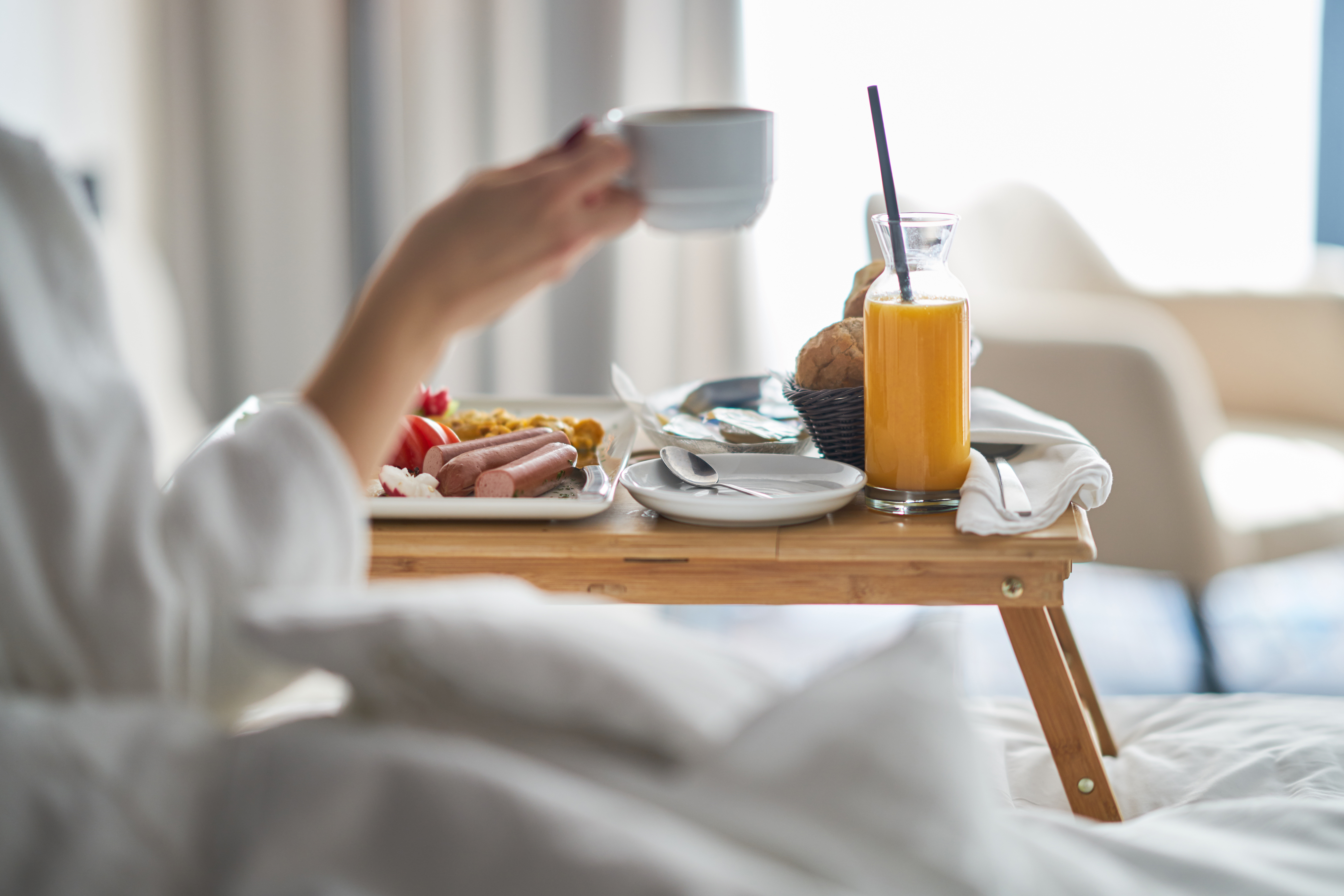 Une femme prenant son petit déjeuner dans une chambre d'hôtel confortable | Source : Shutterstock
