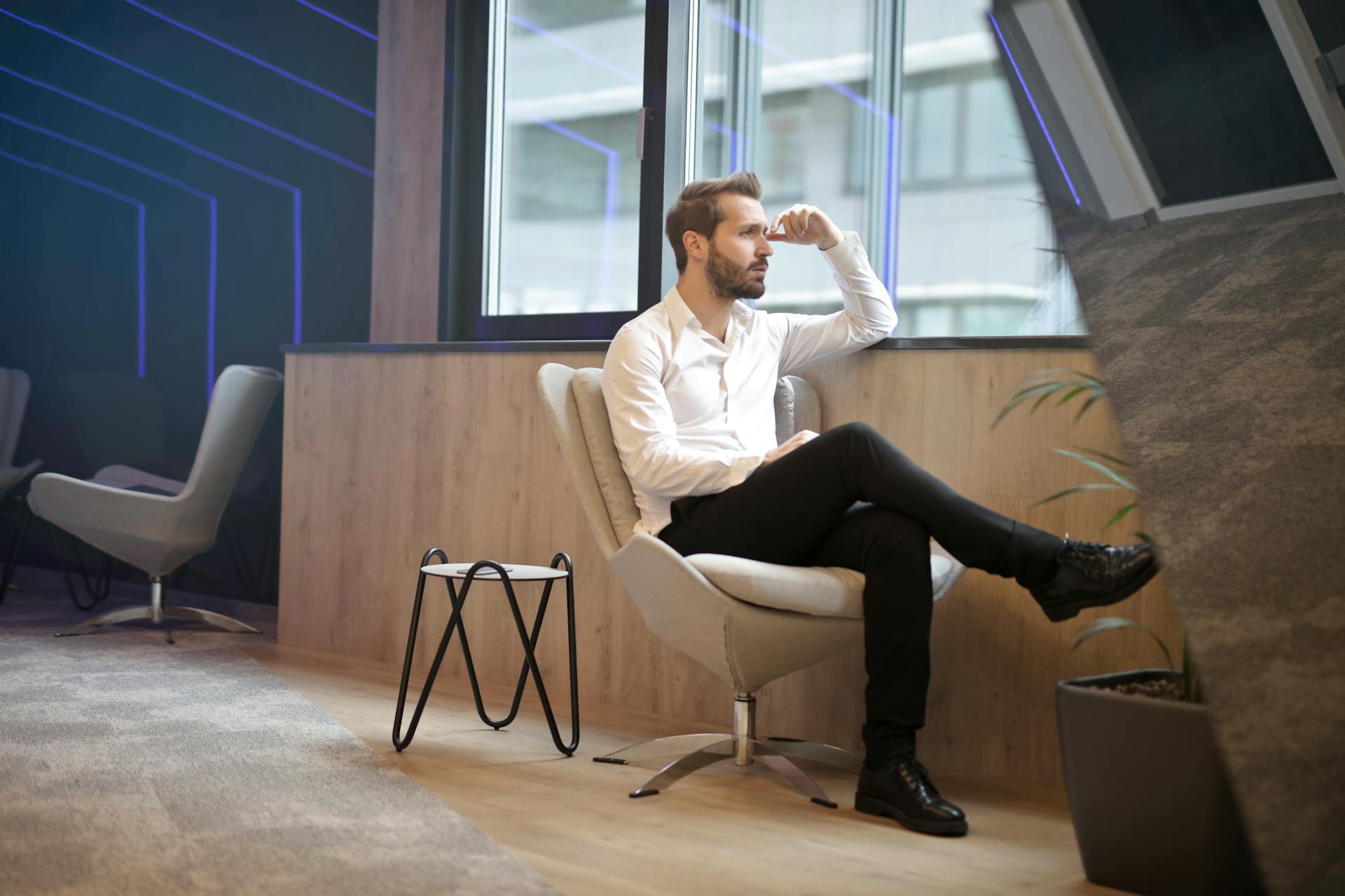 Un homme pensif assis près de la fenêtre dans un bureau | Source : Pexels