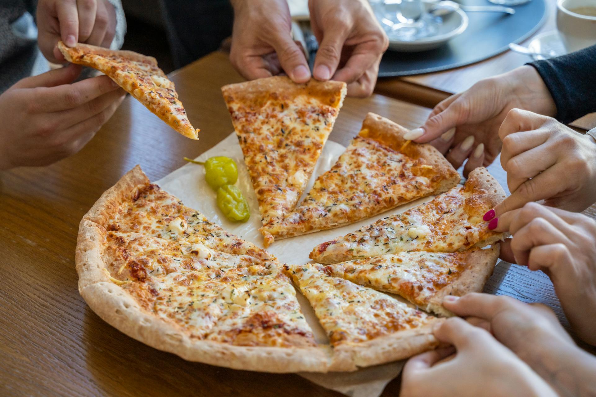 Des personnes prennent des parts de pizza | Source : Pexels