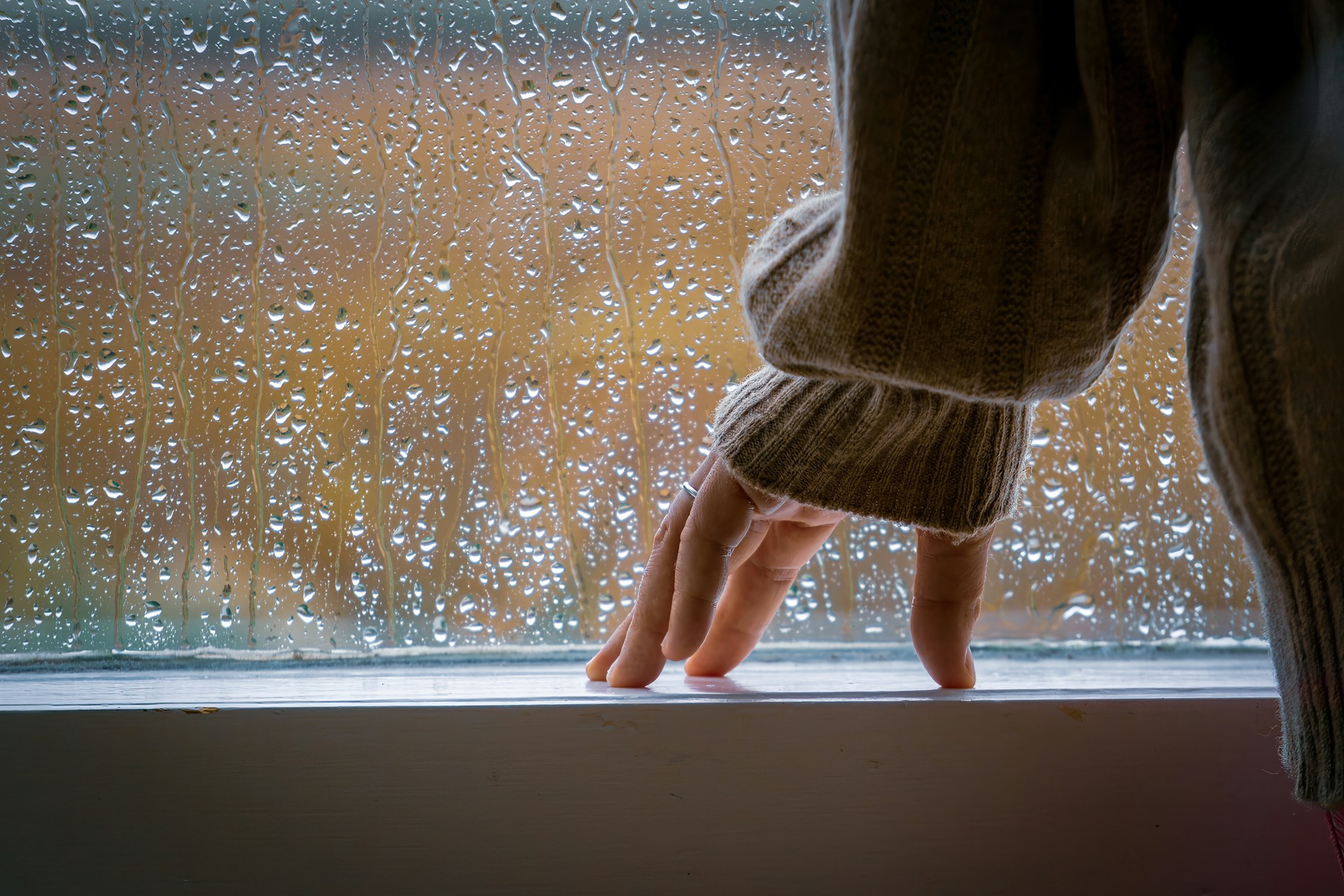 Une femme se tenant près d'une fenêtre et regardant la pluie | Source : Unsplash