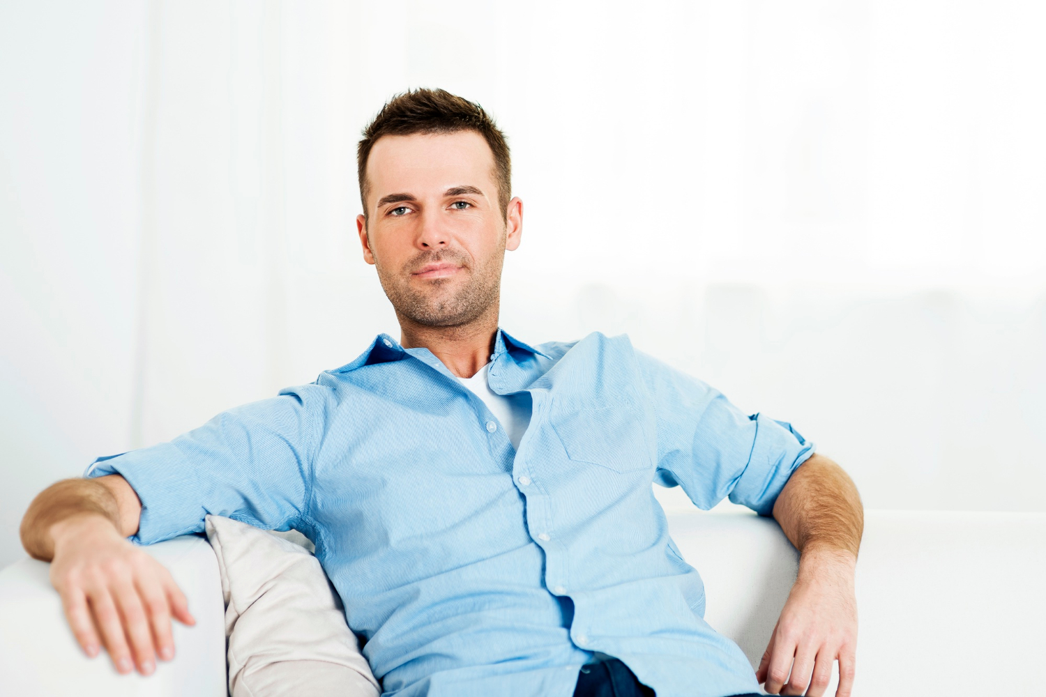Un homme souriant assis sur le canapé | Source : Freepik