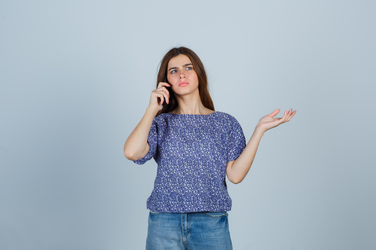 Une jeune femme frustrée qui parle au téléphone | Source : Freepik