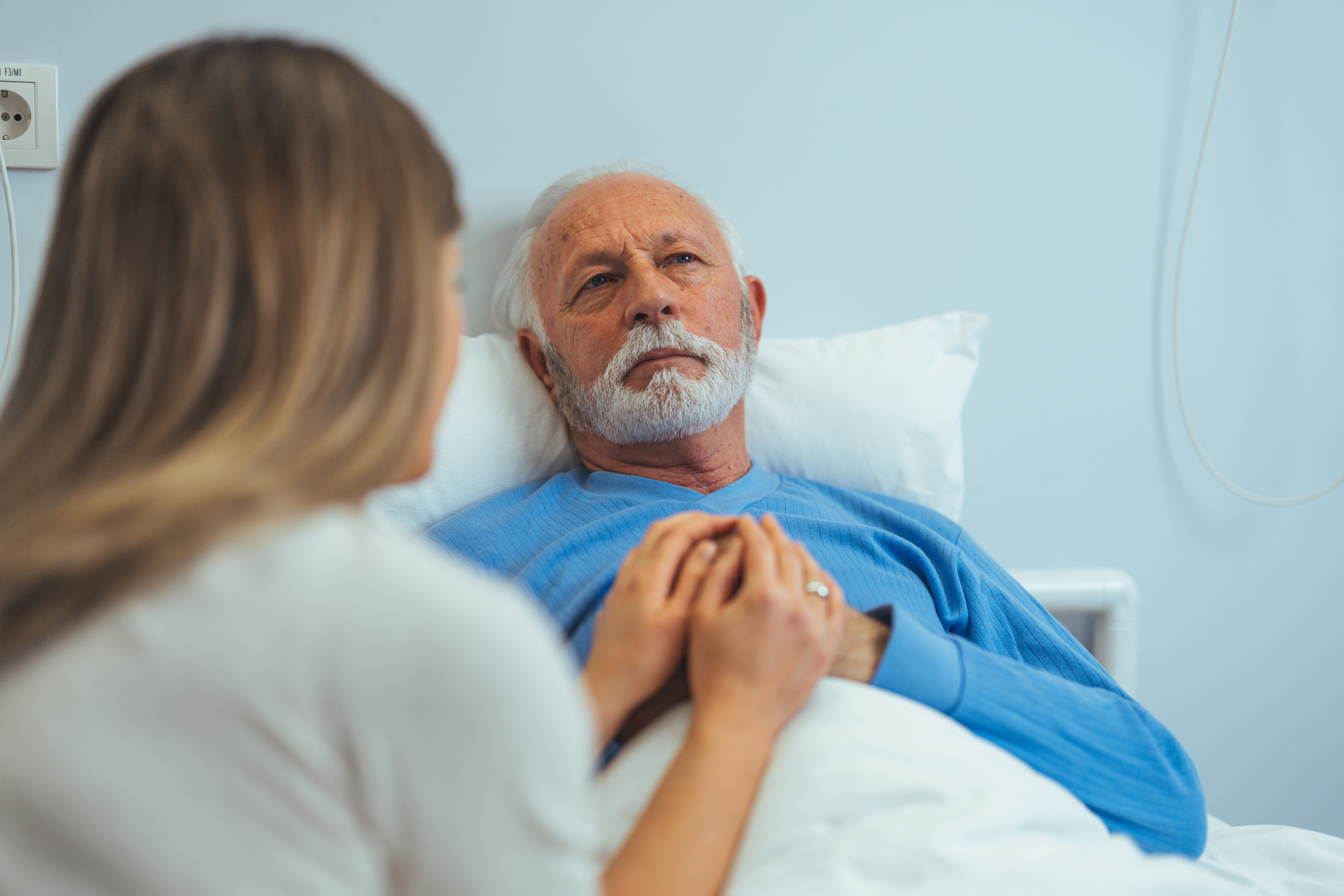 Una mujer visita a un hombre mayor en una habitación de hospital | Fuente: Shutterstock