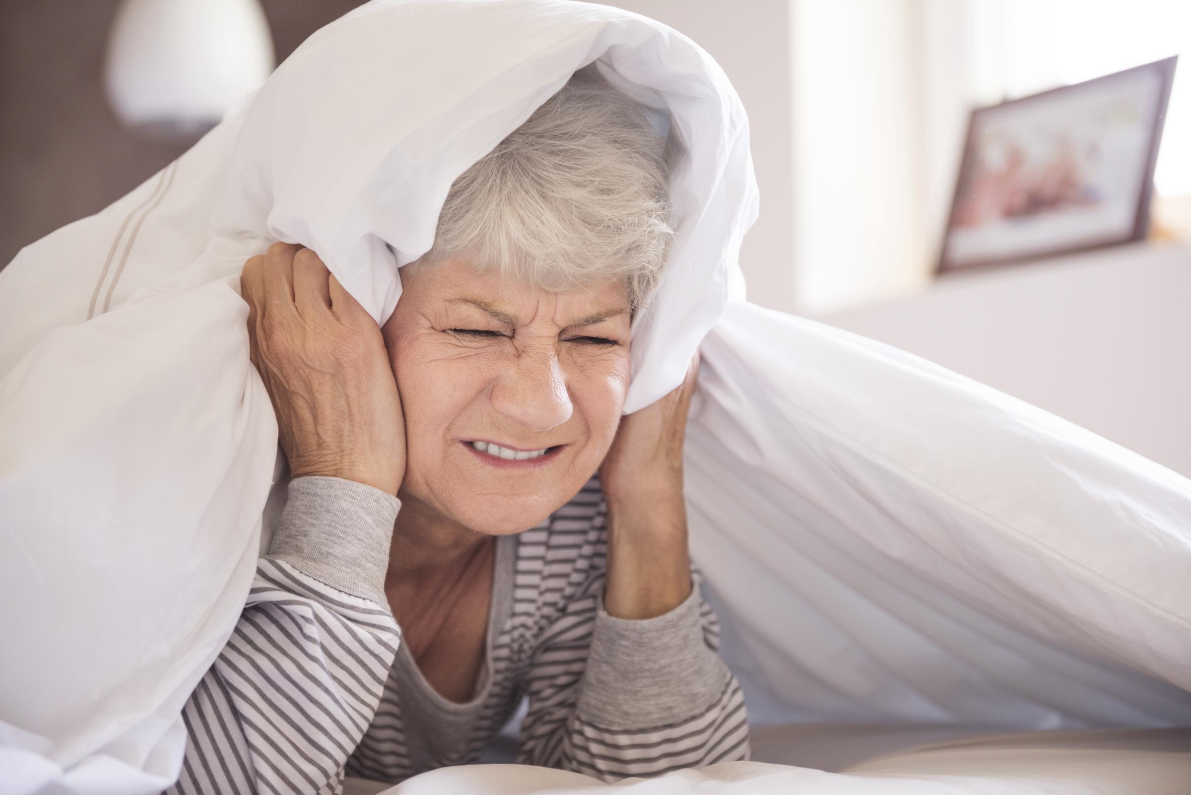 Une femme âgée se couvrant les oreilles | Source : Freepik