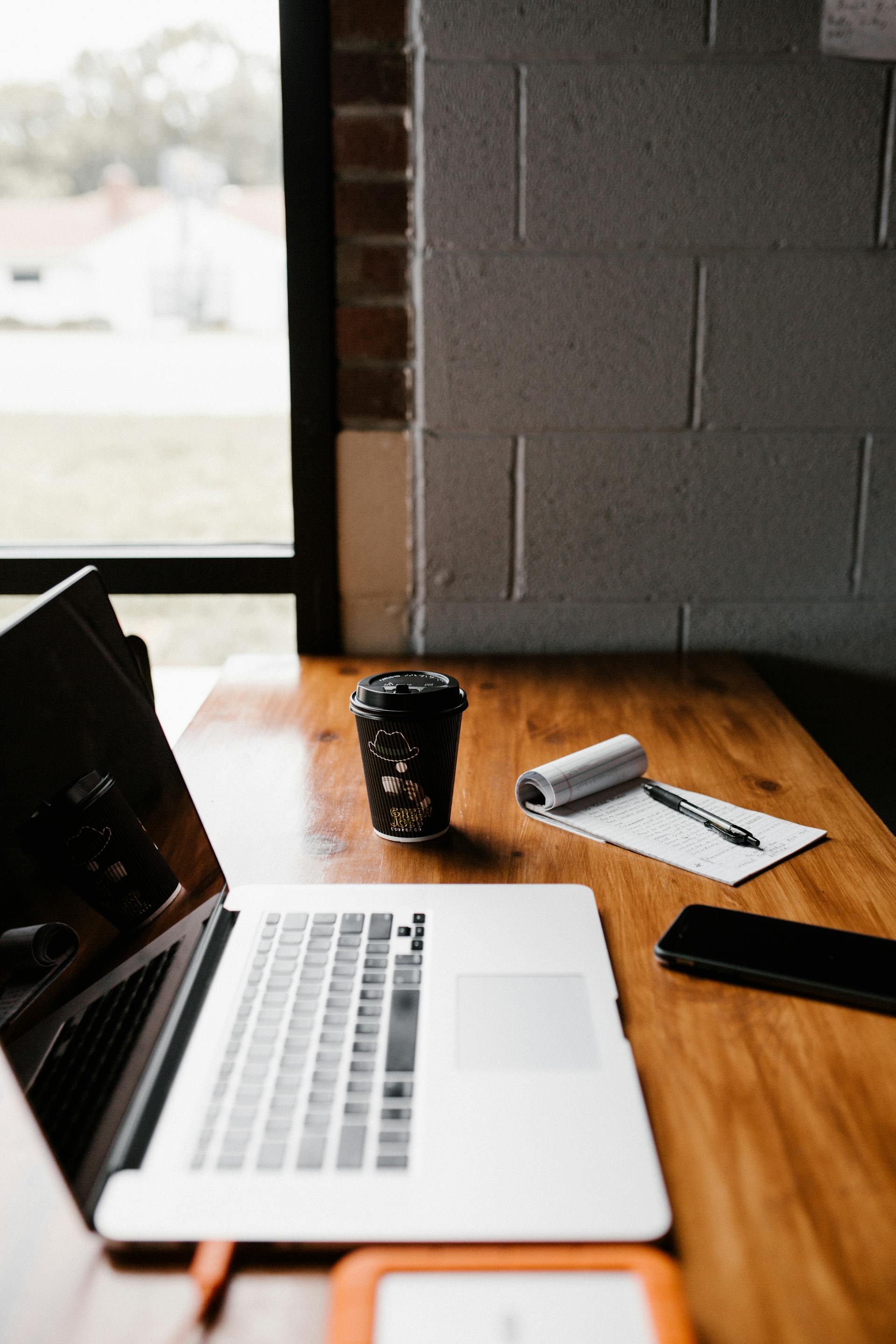 Une tasse de café à emporter à côté d'un ordinateur portable sur un bureau | Source : Pexels