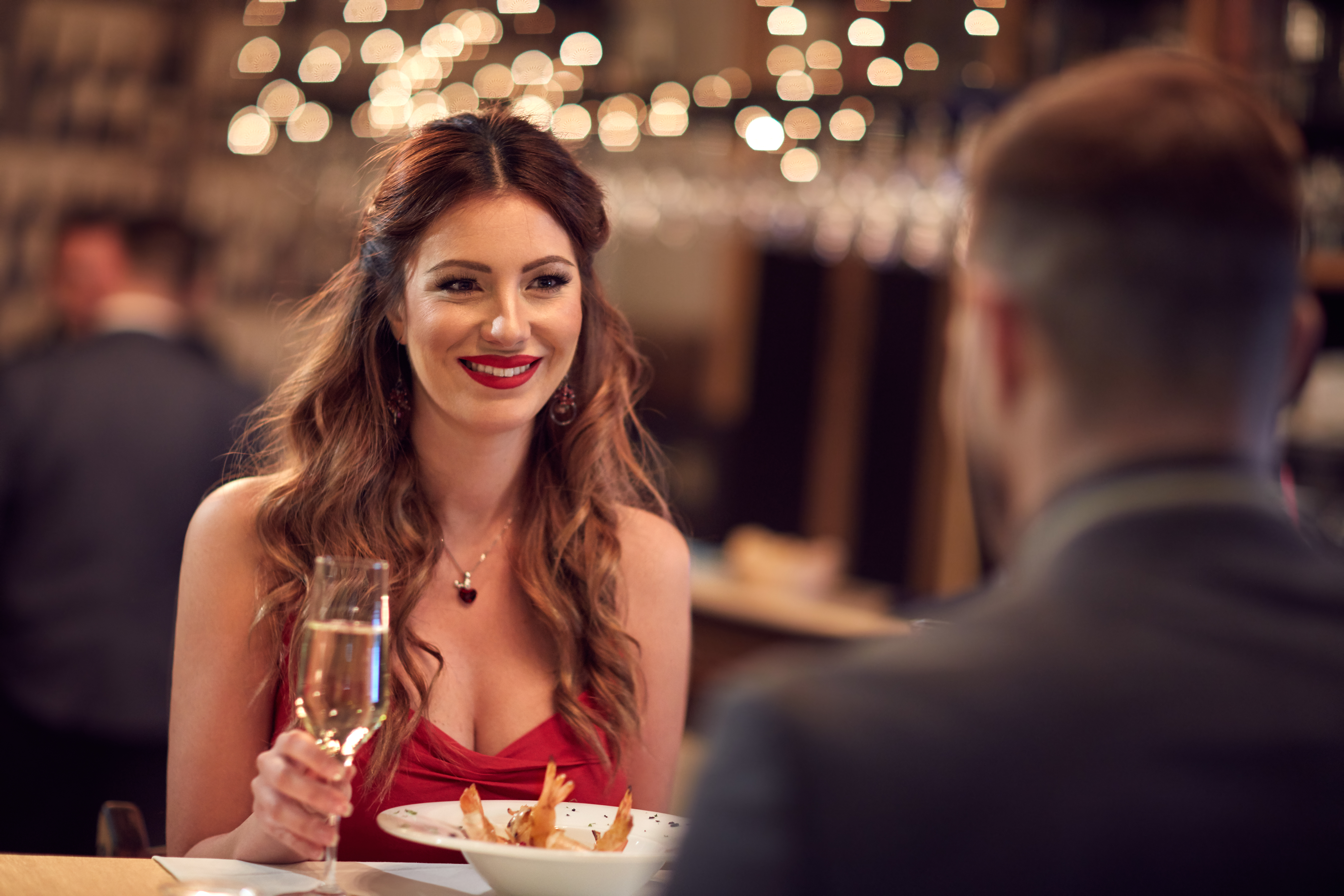 Femme en robe rouge dînant au restaurant avec son petit ami | Source : Shutterstock
