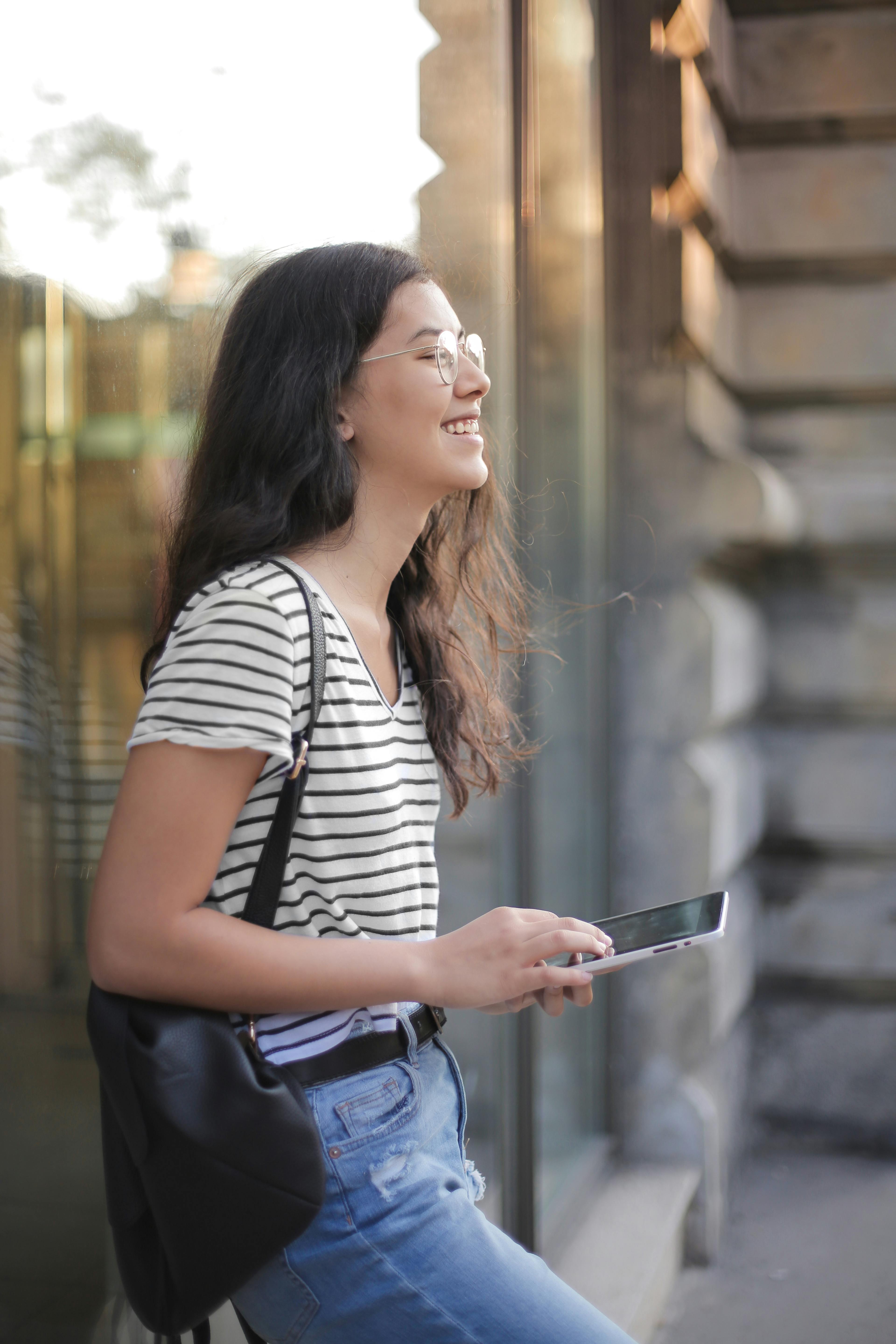 Une femme qui sourit en tenant son téléphone | Source : Pexels