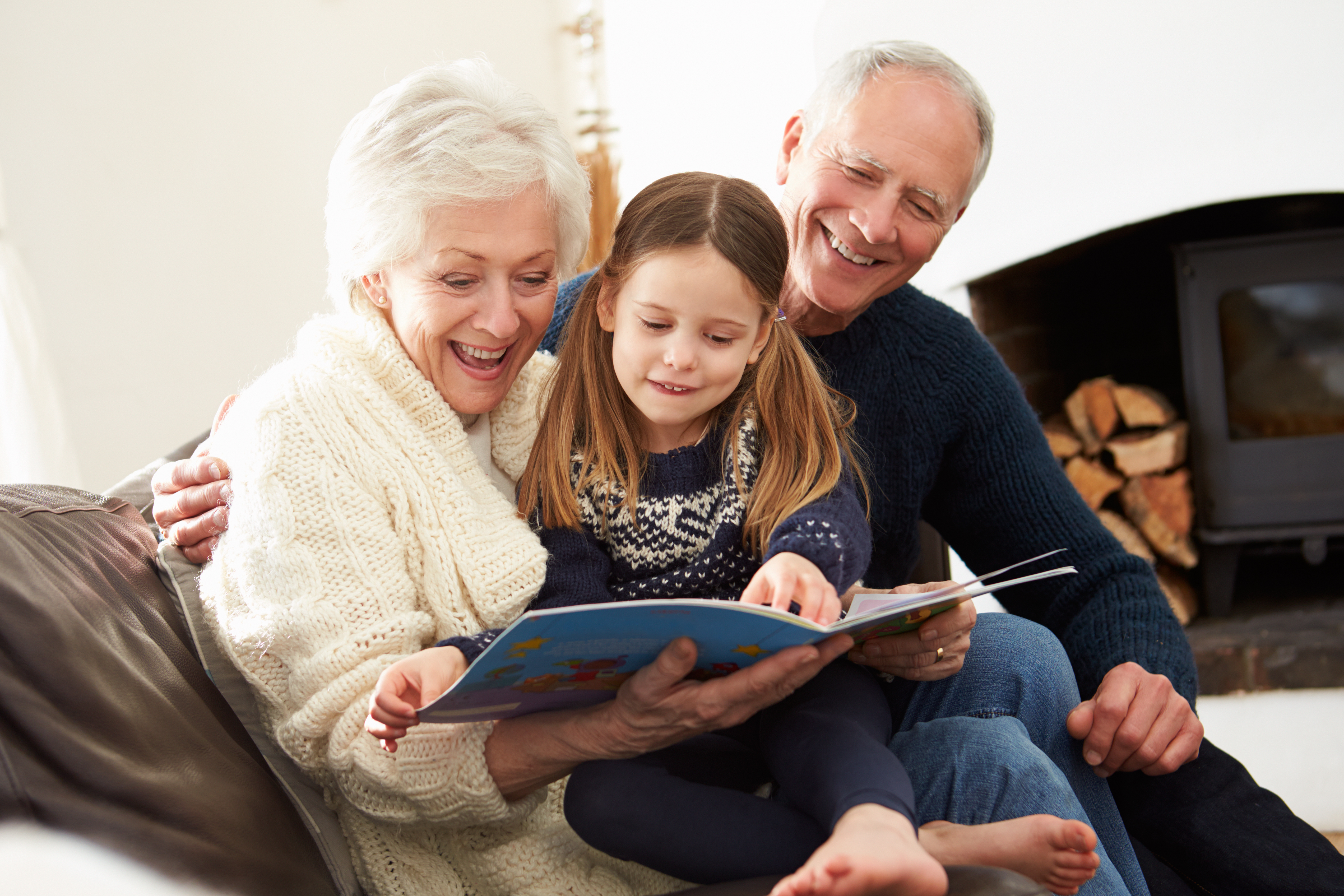 Des grands-parents et leur petite-fille en train de lire un livre ensemble | Source : Shutterstock