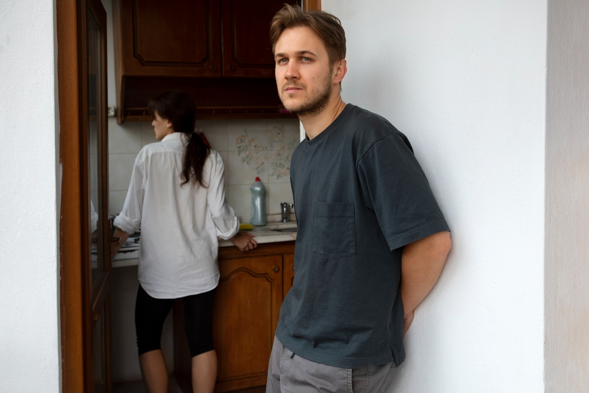 Un homme contrarié se tient près de la porte tandis qu'une femme se tient dans la cuisine | Source : Freepik