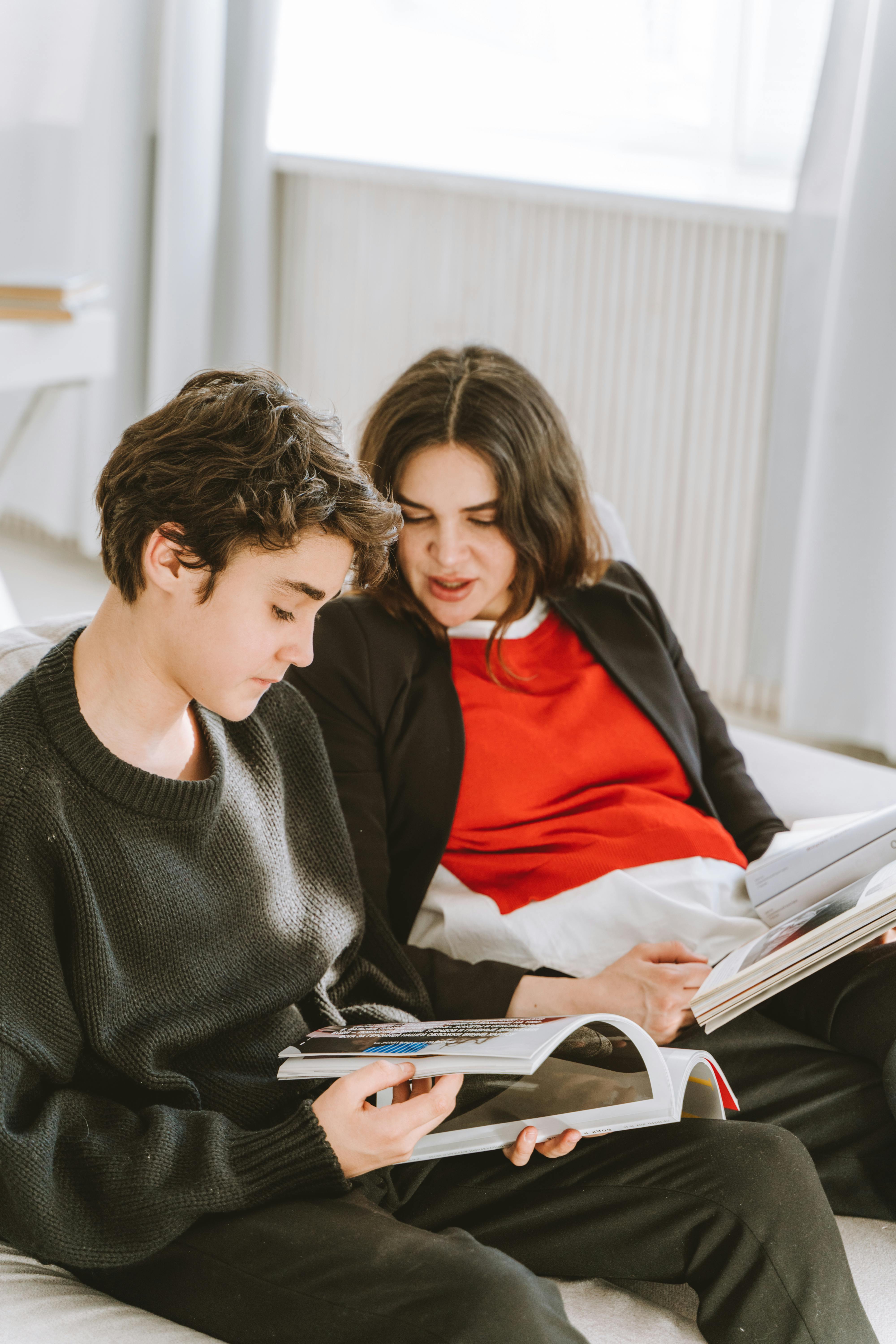 Une femme et son fils assis sur un canapé et regardant des magazines | Source : Pexels