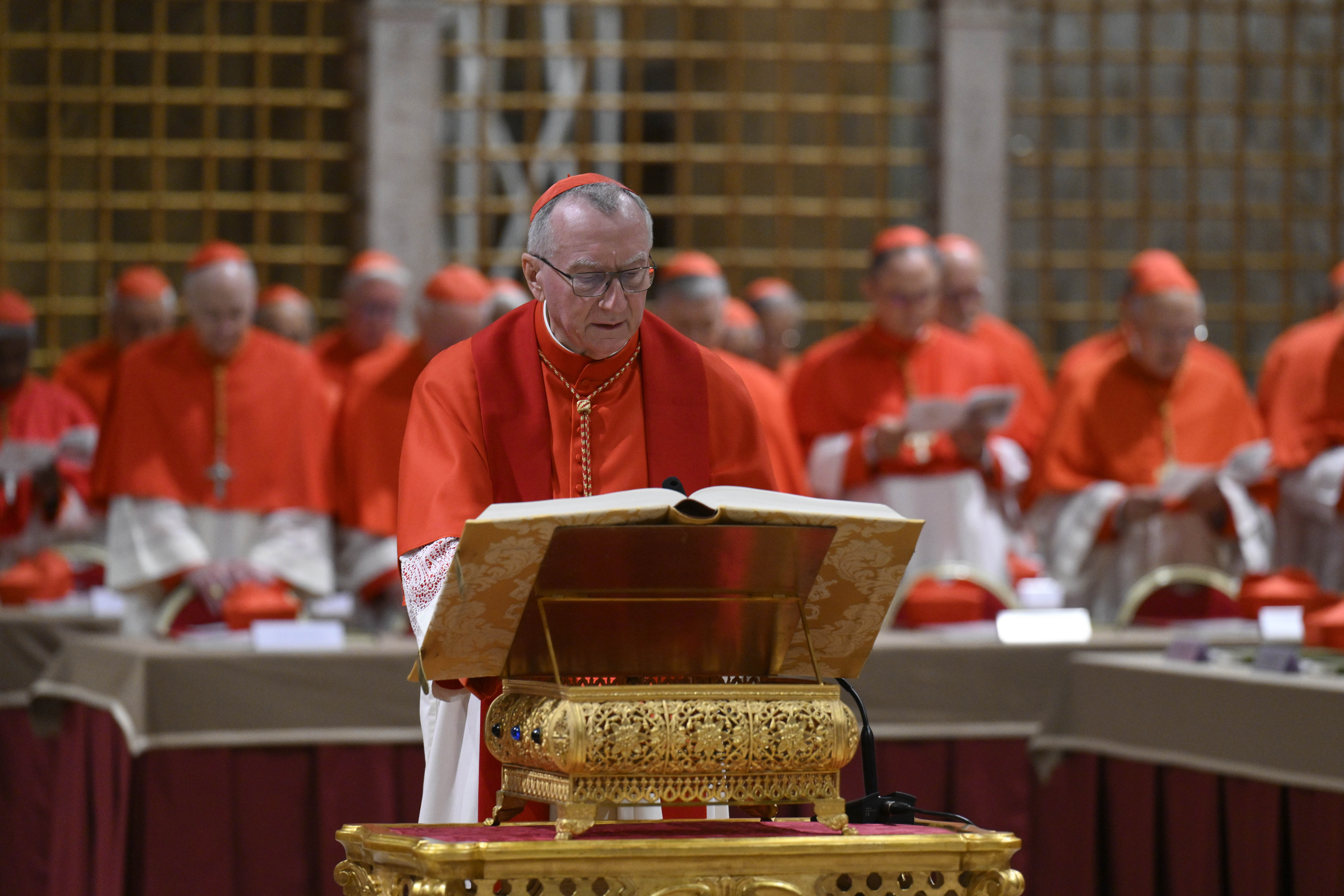 Un cardinal lit l'Évangile tandis que d'autres se tiennent debout en prière pendant le conclave papal au Vatican le 7 mai 2025 | Source : Getty Images