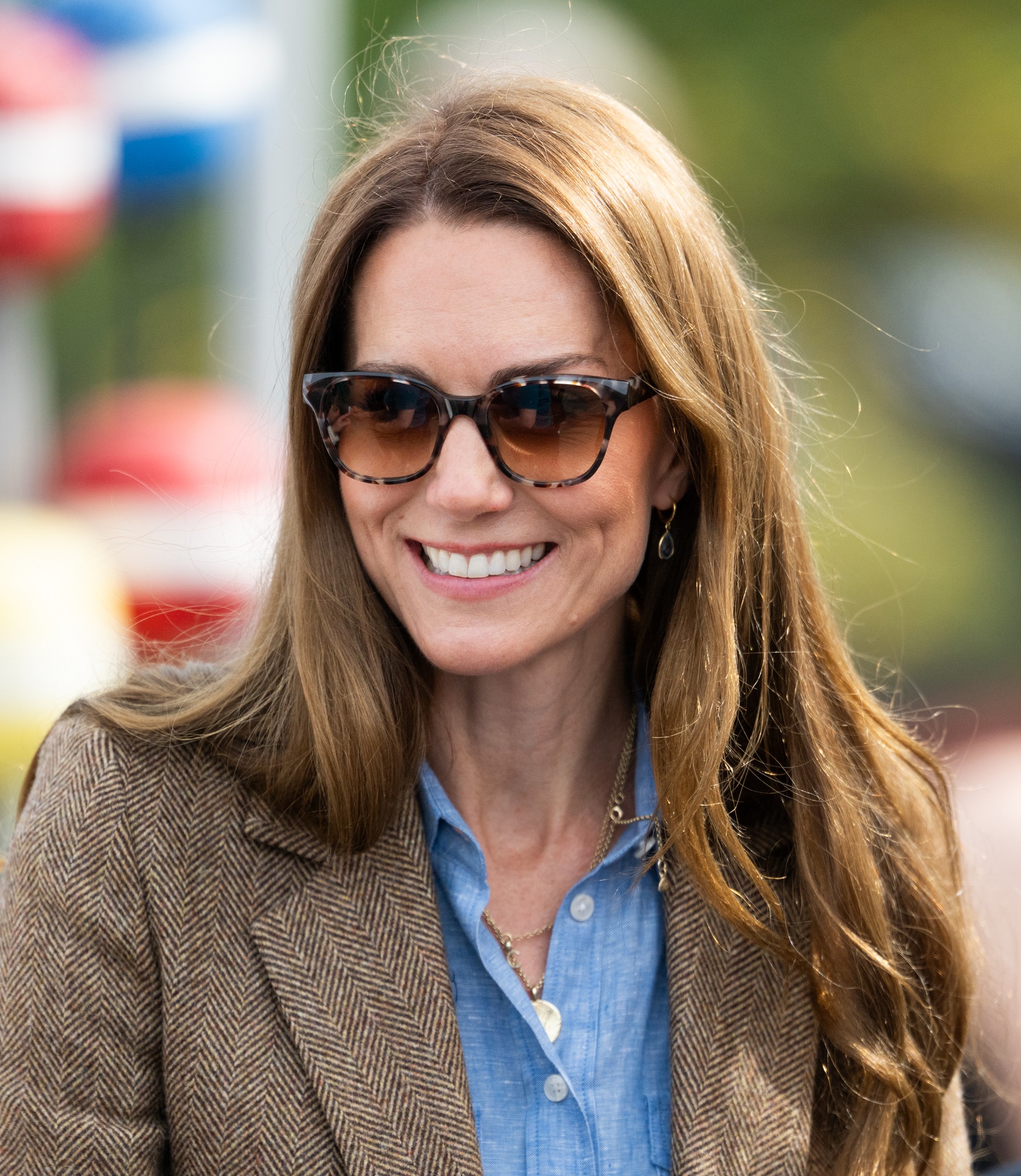 Catherine sourit vivement sous le soleil alors qu'elle visite un marché local à Tobermory, son visage encadré par des cheveux brun doré doucement ébouriffés qui brillent à la lumière. Avec des lunettes de soleil foncées et une expression détendue, elle rayonne de chaleur et d'aisance pendant la sortie.