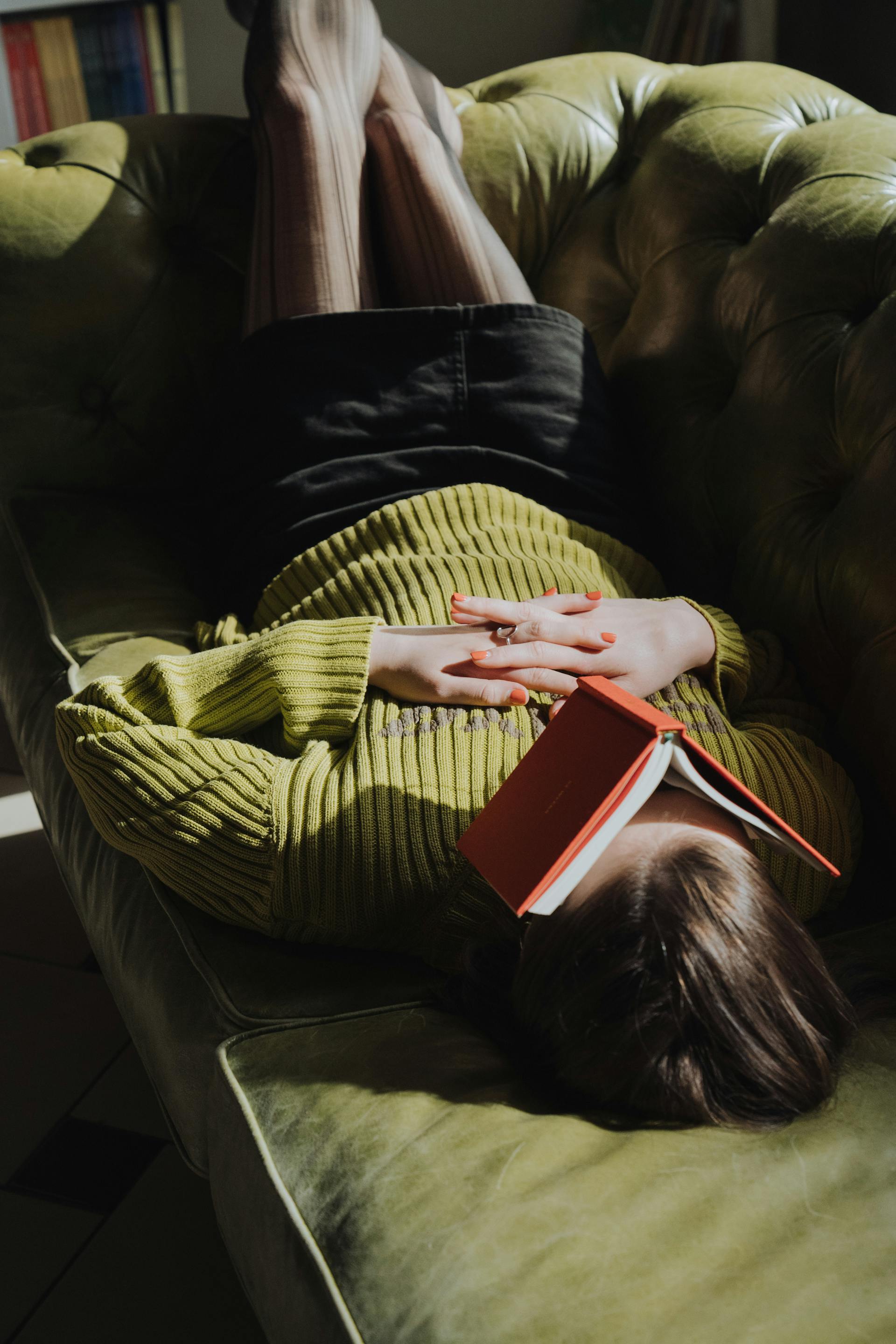 Une femme allongée sur un canapé avec un livre | Source : Pexels